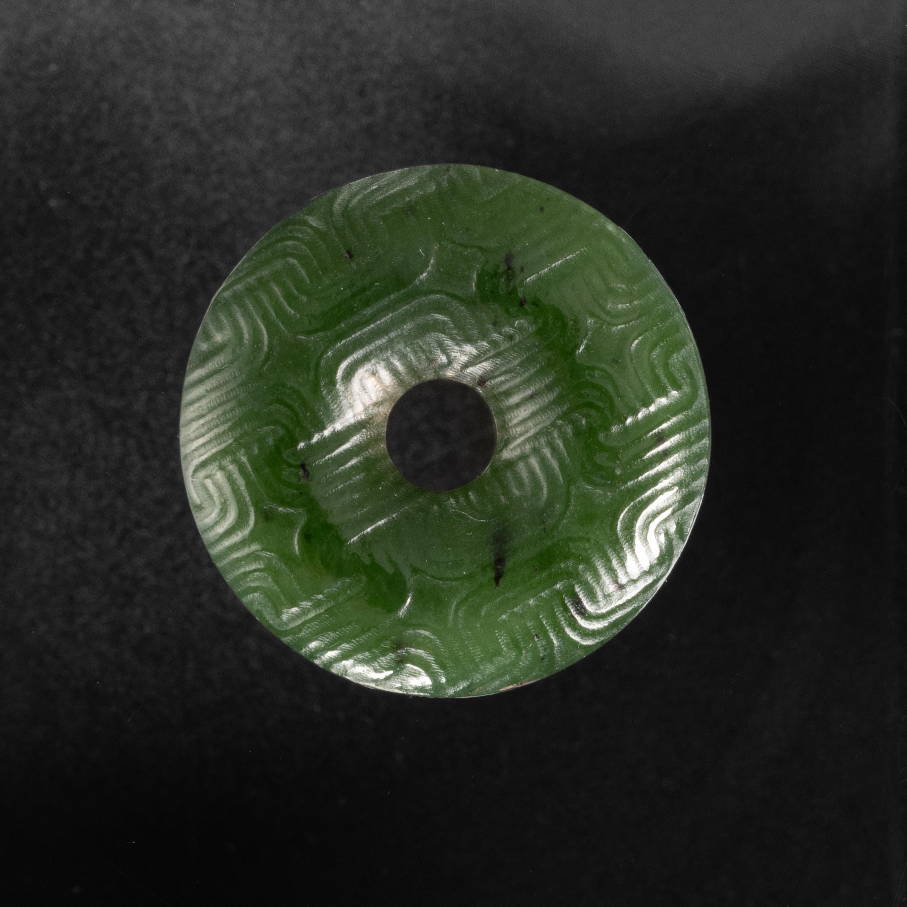 What is being said in the geometric language we see so precisely inscribed into the surface of this jade bi disc? Look closely and you will see the enduring tool marks: shaggy grooves made by a stick of bamboo that had been first dipped into a paste