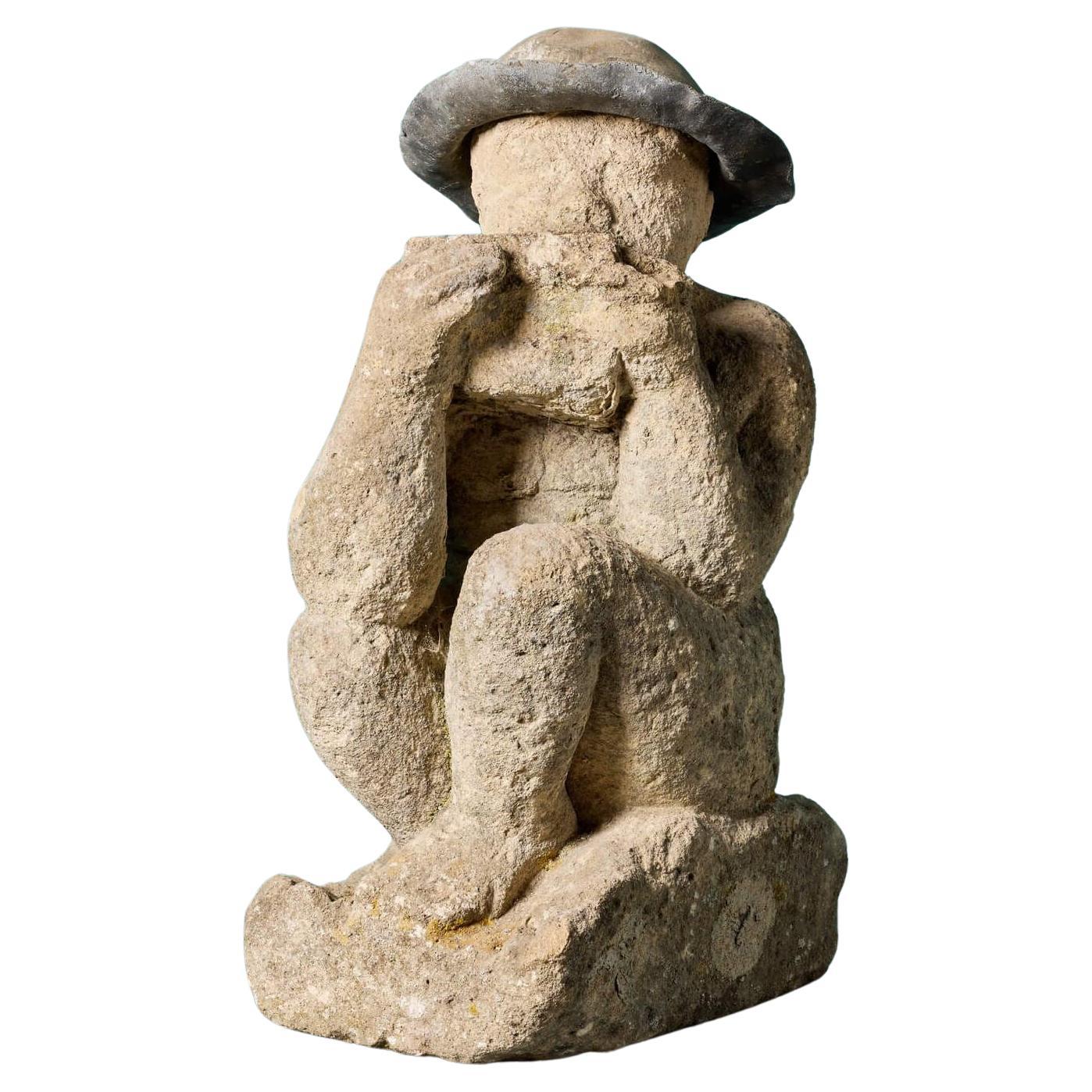 Estatua antigua de piedra caliza tallada de un niño tocando la gaita