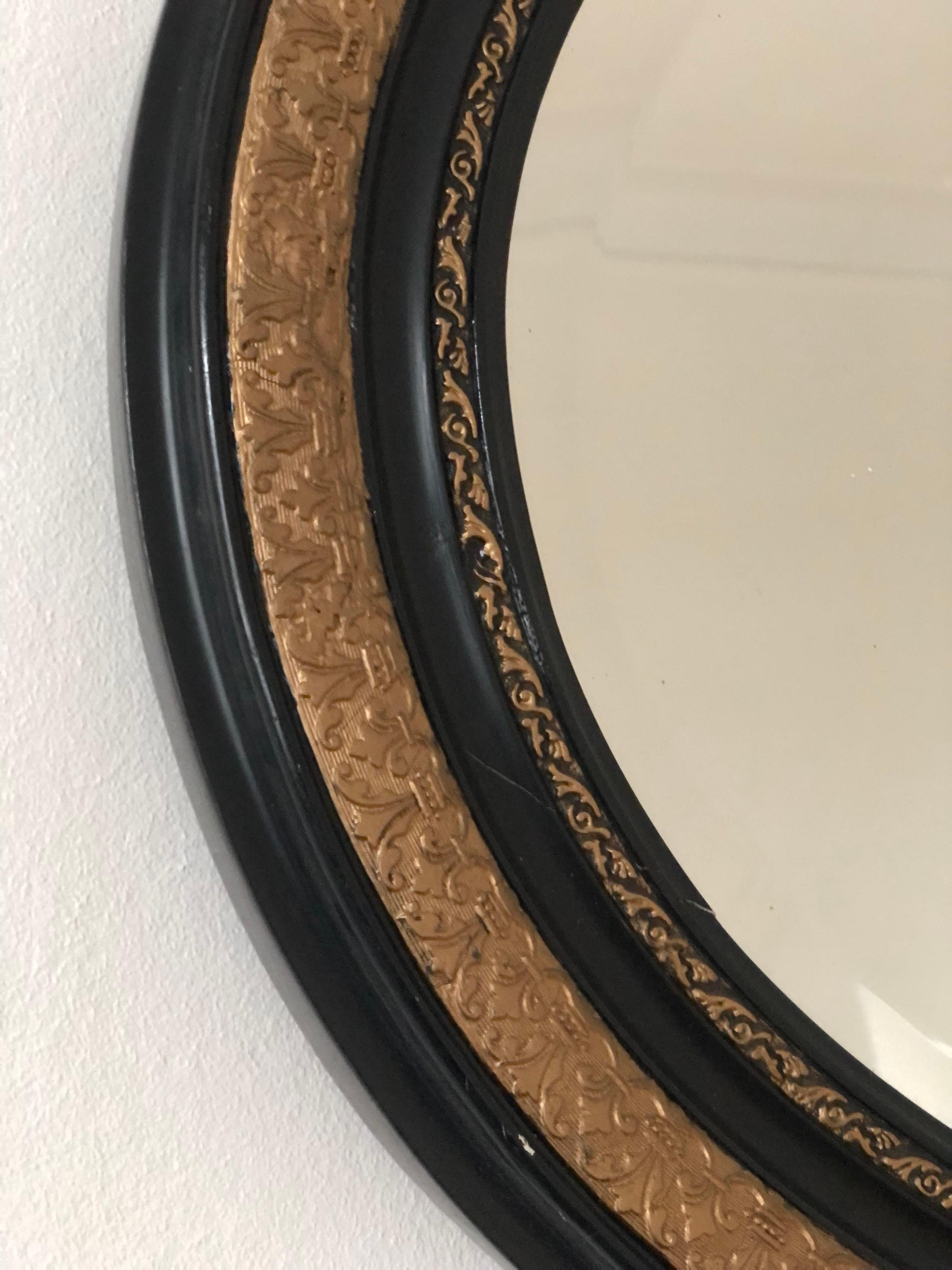 19th Century oval Louis Philippe mirror in black and gold. Beautiful richly carved mirror from 1898 and restored in 1996. The frame has been refurbished and the glass has been 
renewed with facet cut glass. This proces is described on the