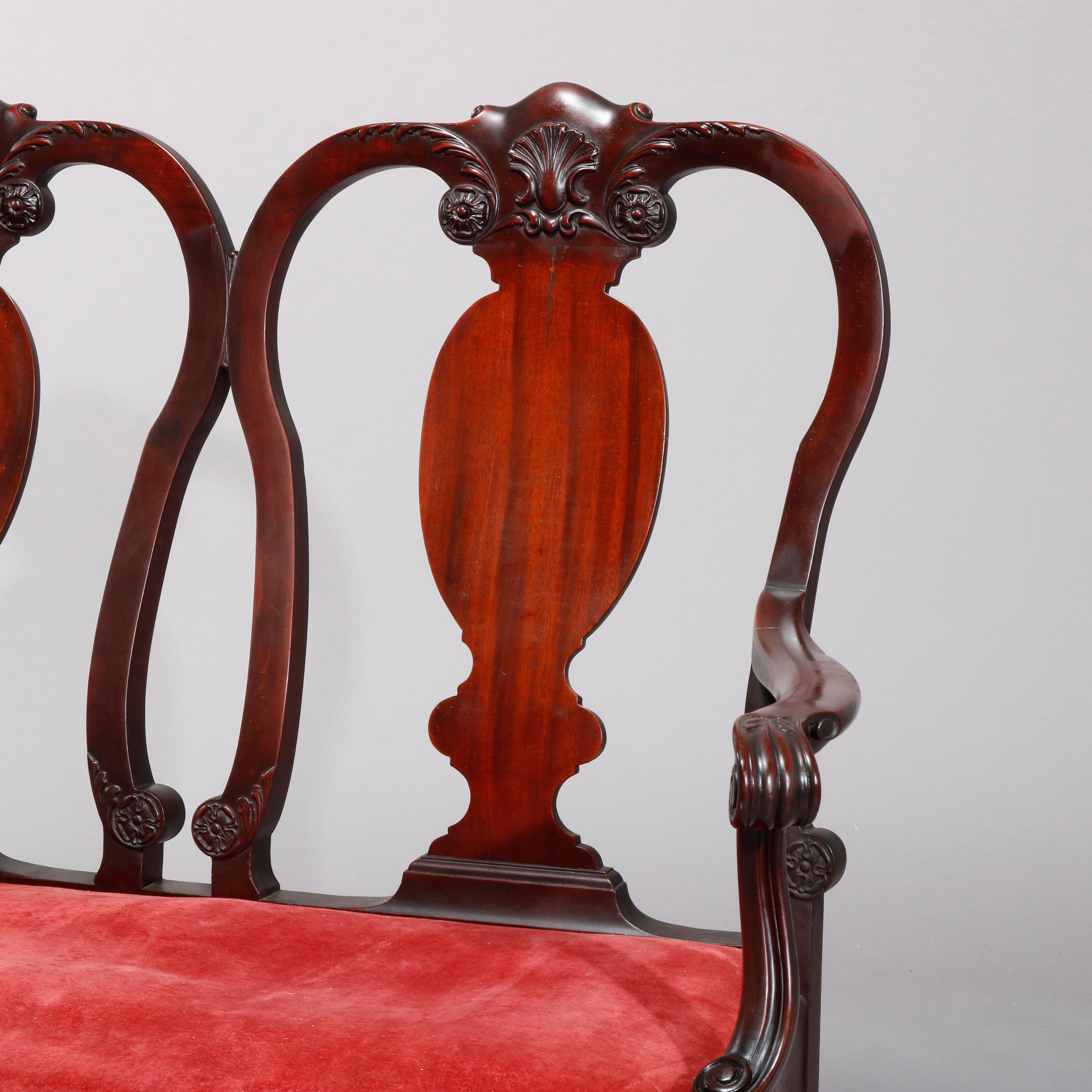 An antique English Chippendale style double chair of settee offers mahogany frame with carved shell and foliate crests over violin form slat backs surmounting upholstered seat with scroll arms, raised on cabriole legs terminating in paw feet, circa