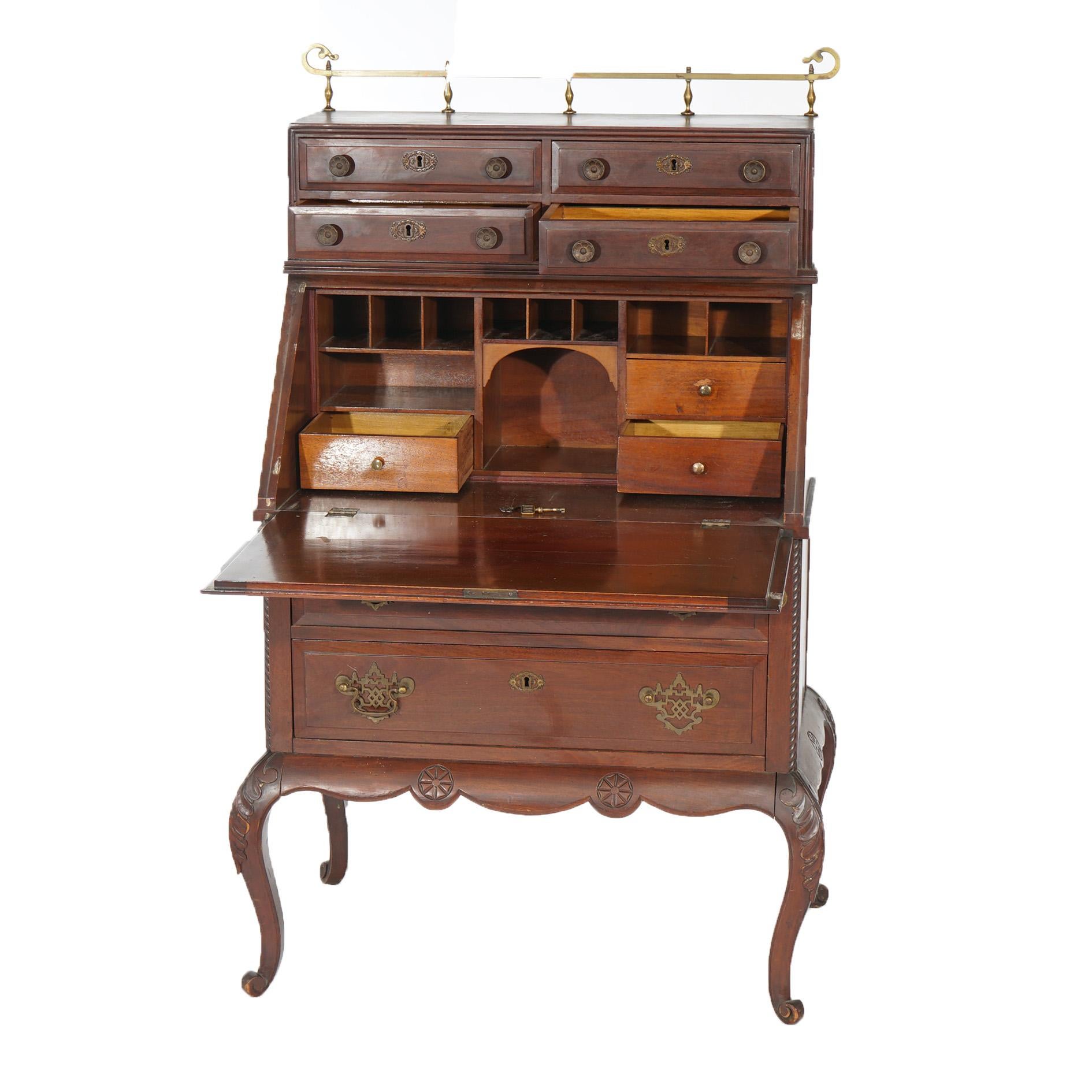 An antique secretary offers mahogany construction with upper brass gallery over upper case with drawers over slant-front desk with carved patera reserve, raised on cabriole legs, c1910

Measures - 55.75