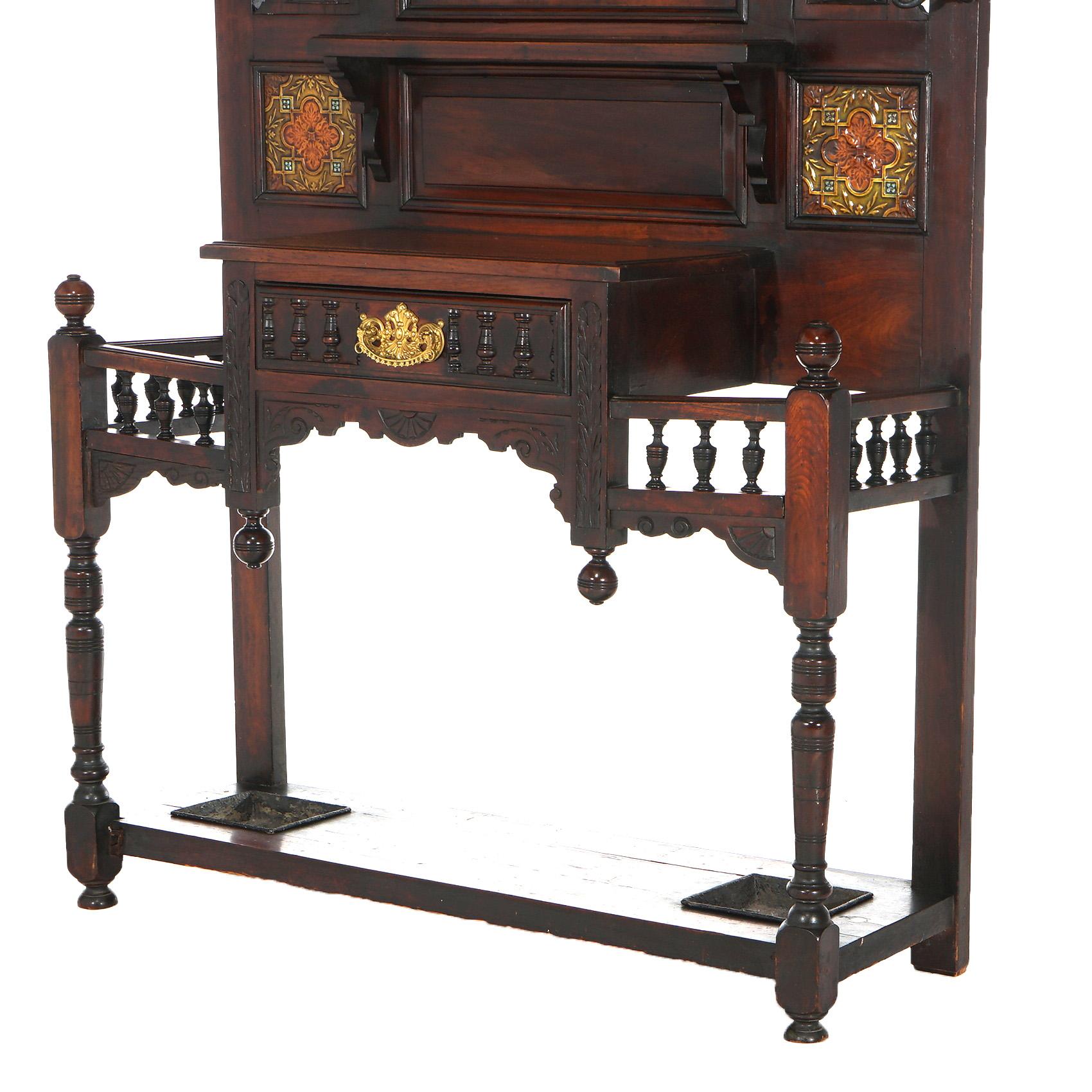 ***Ask About Reduced In-House Delivery Rates - Reliable Professional Service & Fully Insured***
Antique Carved Mahogany Hall Tree with Decorative Embossed Ceramic Tile, Shield Form Mirror and Flanking Spindled Umbrella Rails, C1900

Measures - 83