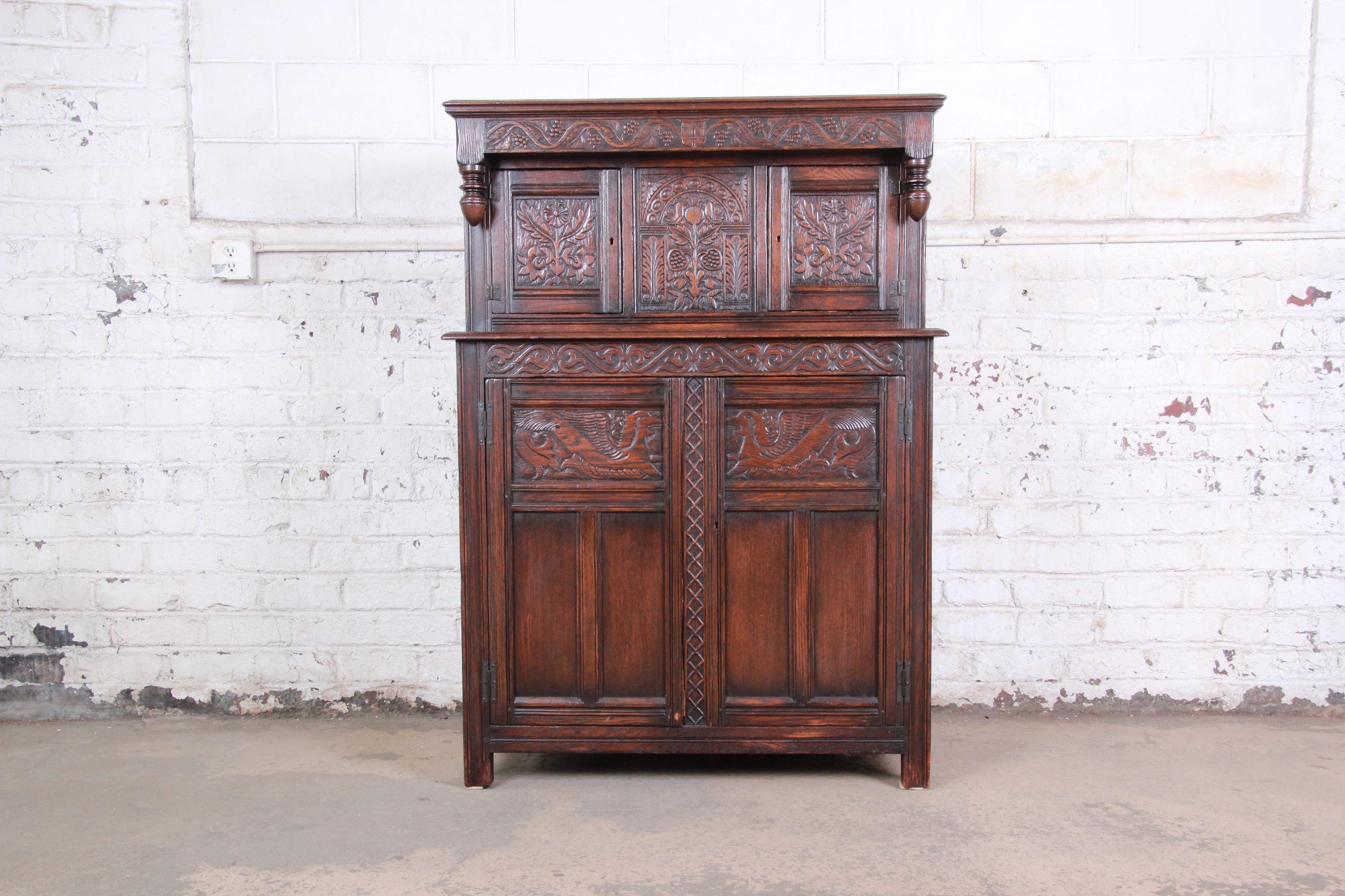 An exceptional antique carved oak bar cabinet by Kensington Furniture Co. of New York, circa 1920s. The cabinet features solid oak construction with beautiful carved wood details. It offers ample storage, with two cabinets behind carved doors at the