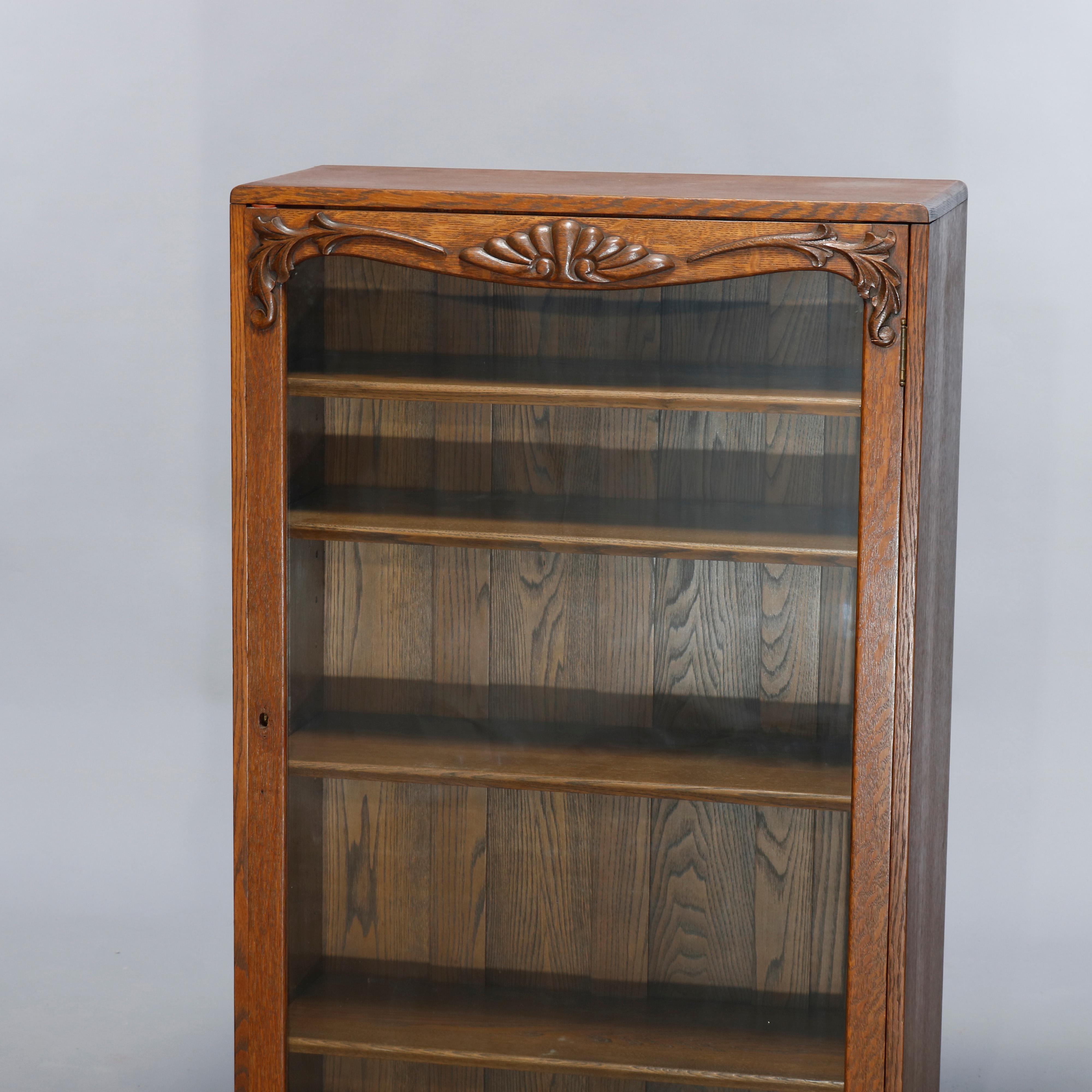 Antique diminutive bookcase offers oak construction with stylized carved shell crest over single glass door opening to shelved interior and raised on stylized paw feet, c1910

Measures: 48.75