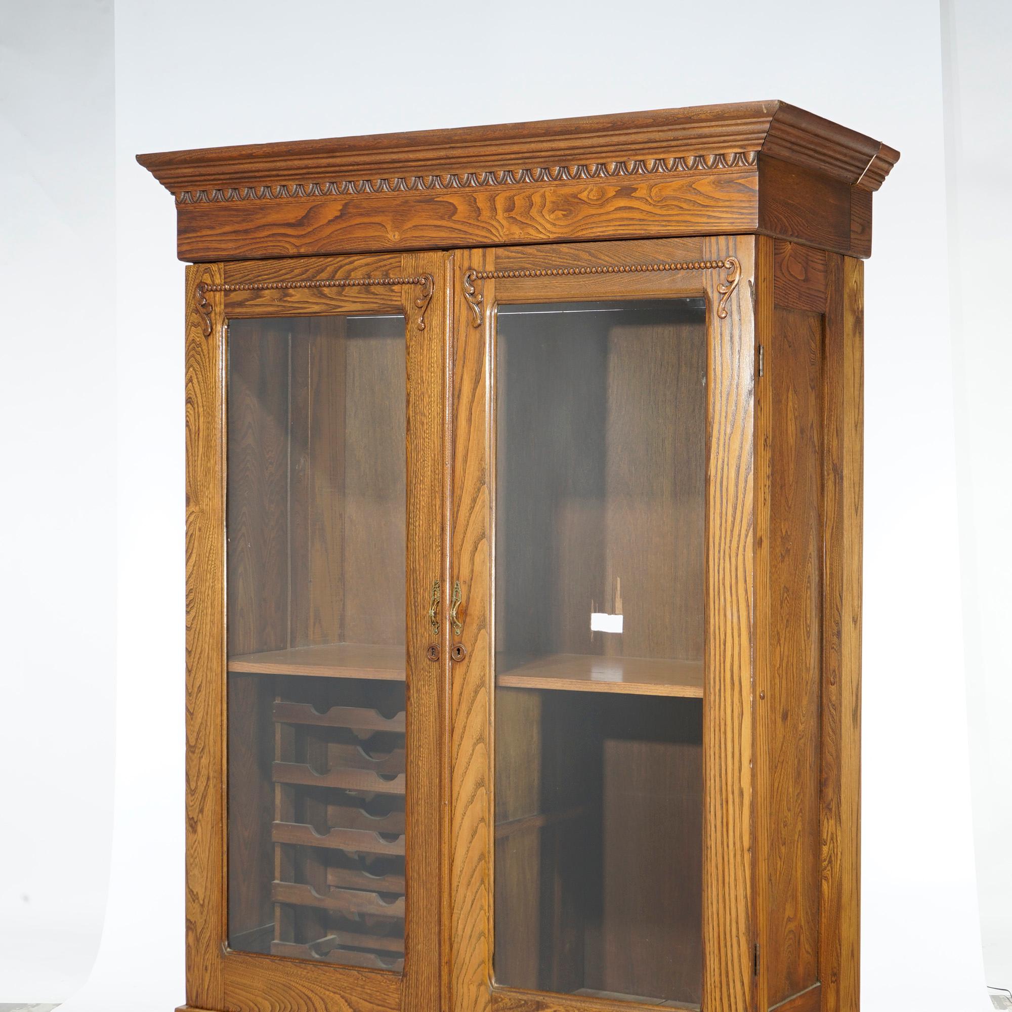Américain Bibliothèque ancienne à double porte en chêne sculpté avec porte-bouteilles, vers 1920 en vente