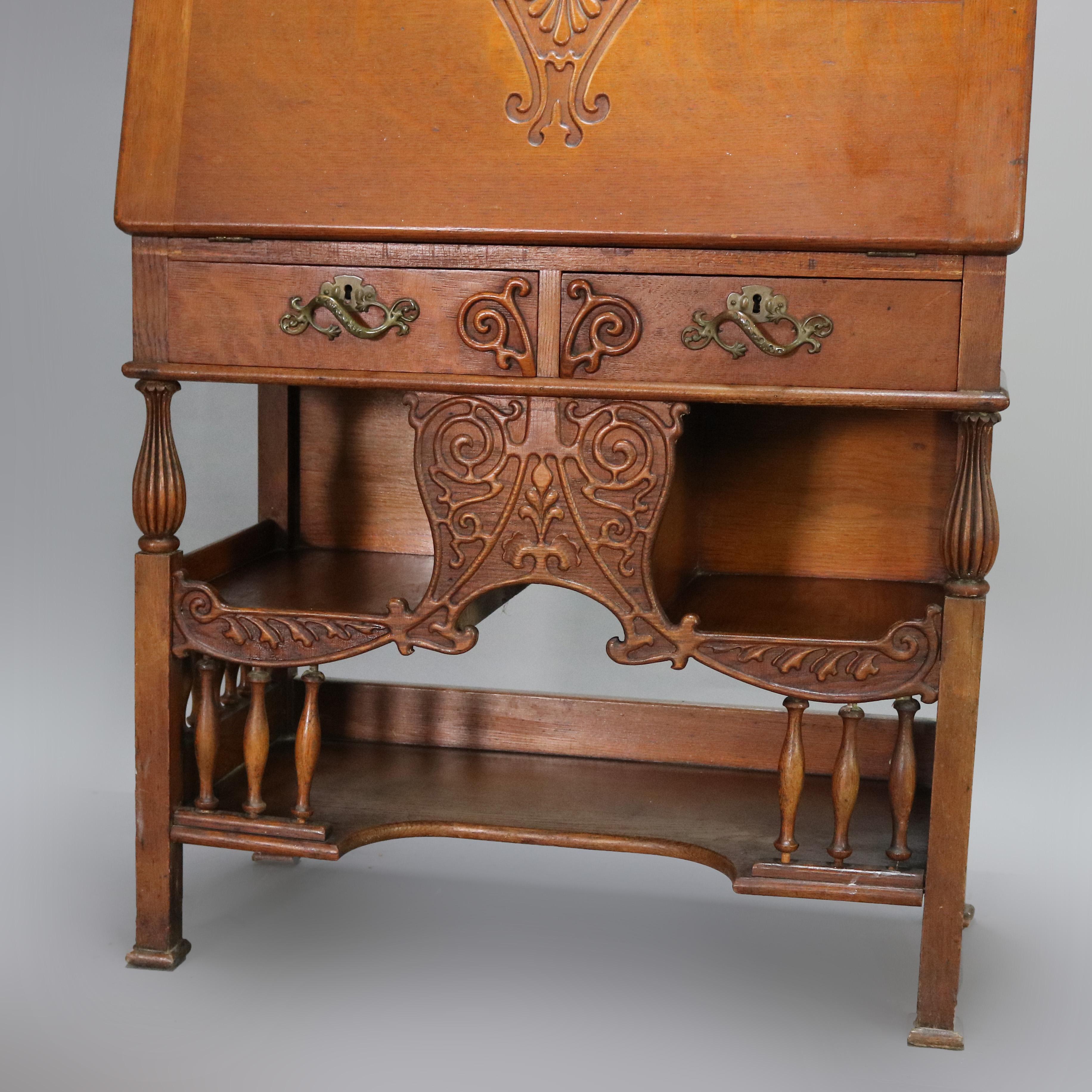 An antique RJ Horner School Cowboy desk offers oak construction with gallery having carved scroll rail over mirrored upper with central drawer and flanking cabinets over slant front desk opening to writing surface and pigeon holes surmounting lower