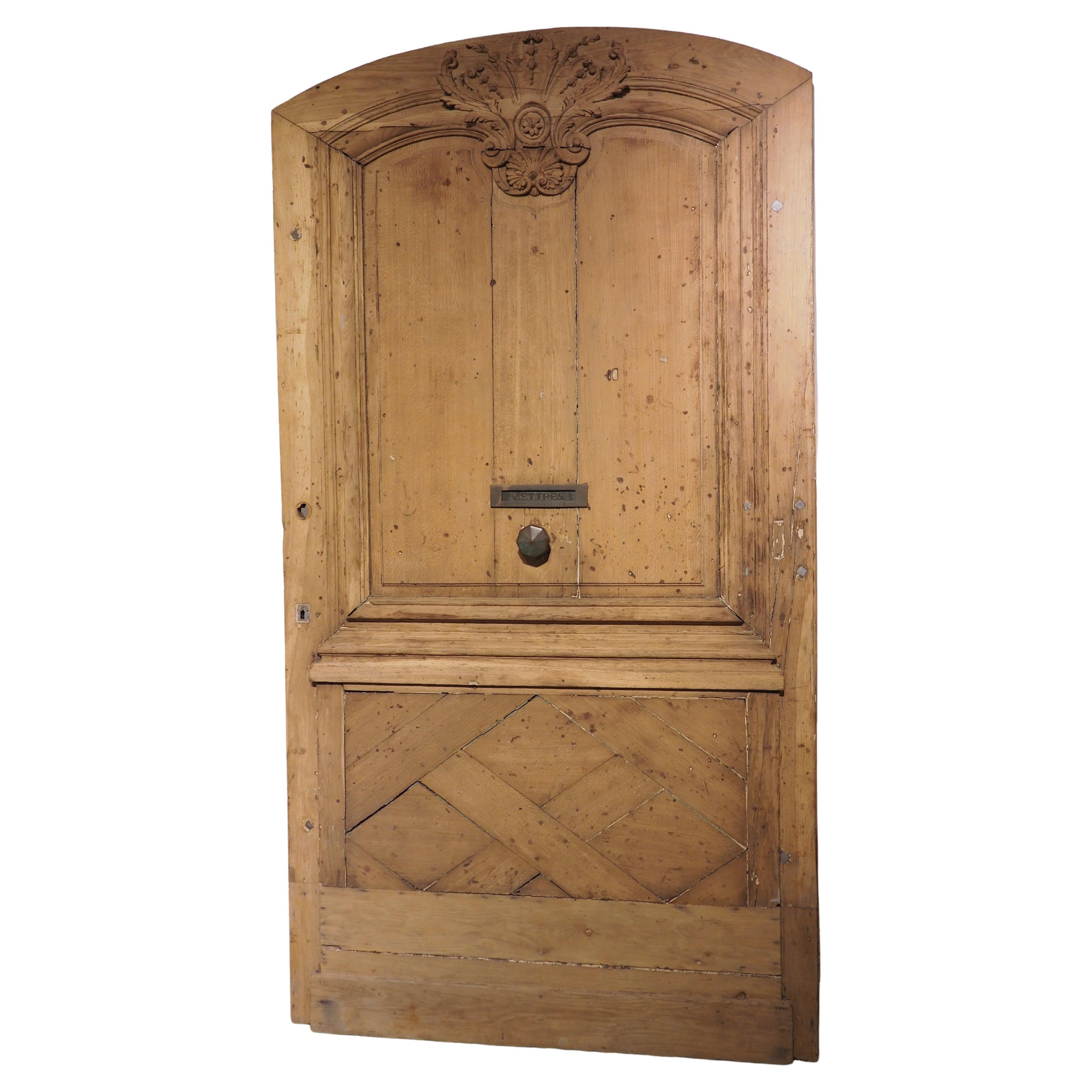 Removed from a large property in Northern France, this antique oak entry door was hand-carved circa 1850. The large door (95 ¾ H x 51 ½ W x 1 ¾ D) has an octagonal metal knob in the center beneath a mail slot marked “Lettres”.

On the upper half