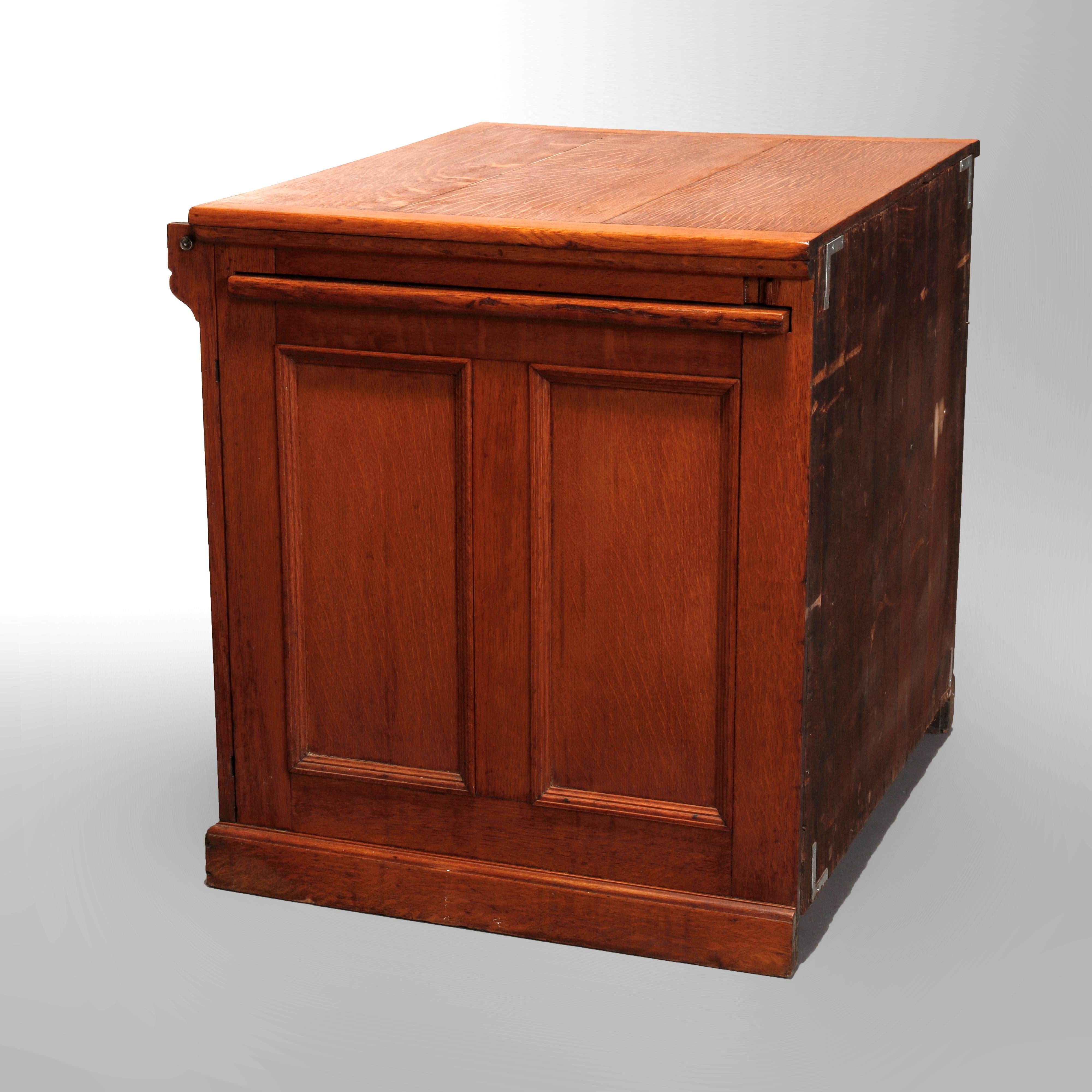 An antique library file cabinet in the manner of Macey offers oak construction with paneled case having four drawers with foliate carved cup handles and side slide out work tray, circa 1900.

Measures: 30
