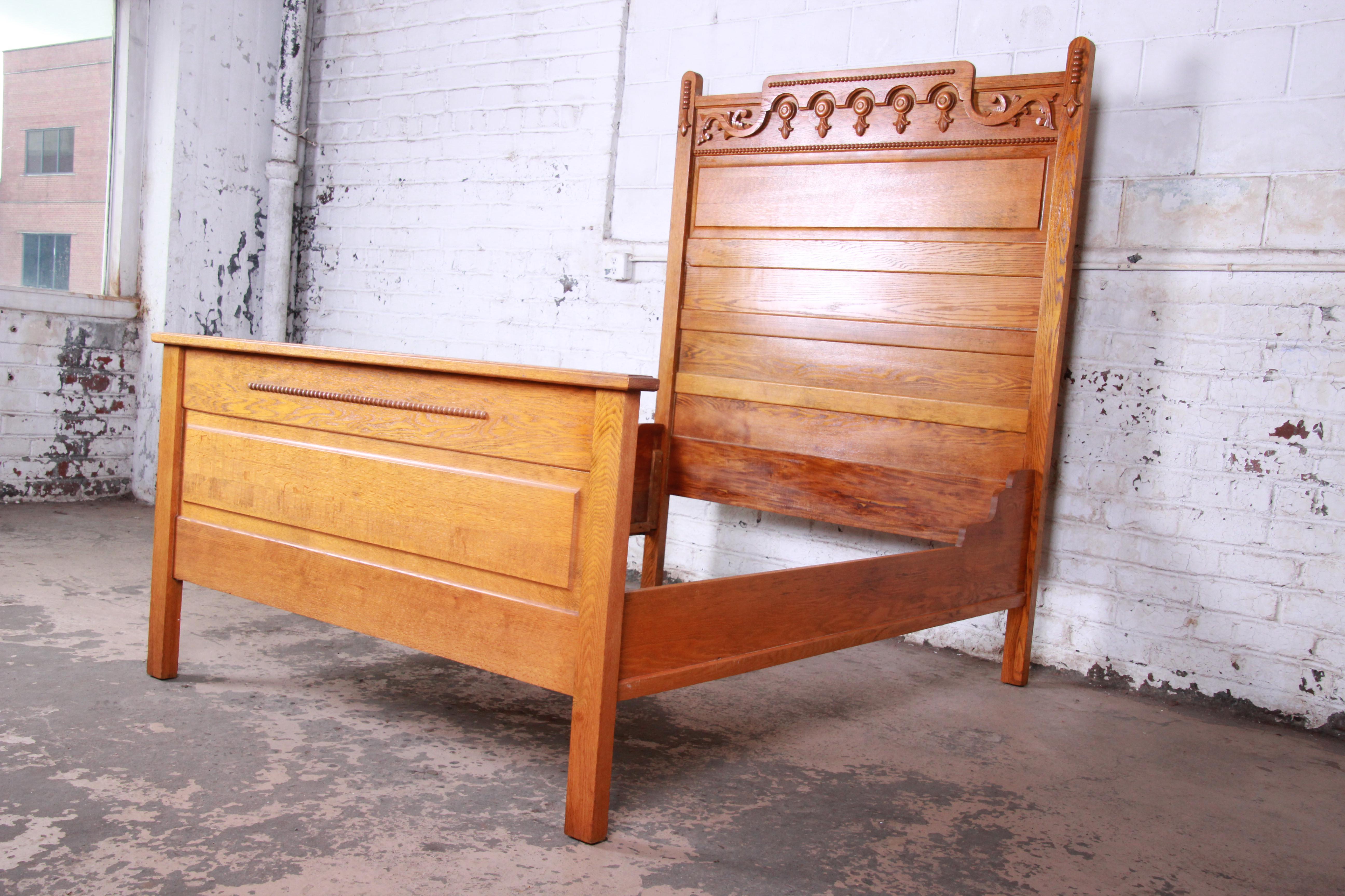 A gorgeous antique carved solid oak full size bed frame. The bed features beautiful wood grain and nice carved details. It is solid, sturdy, and fully functional. The headboard impressively stands at over 6 feet tall. The bed is in very good vintage