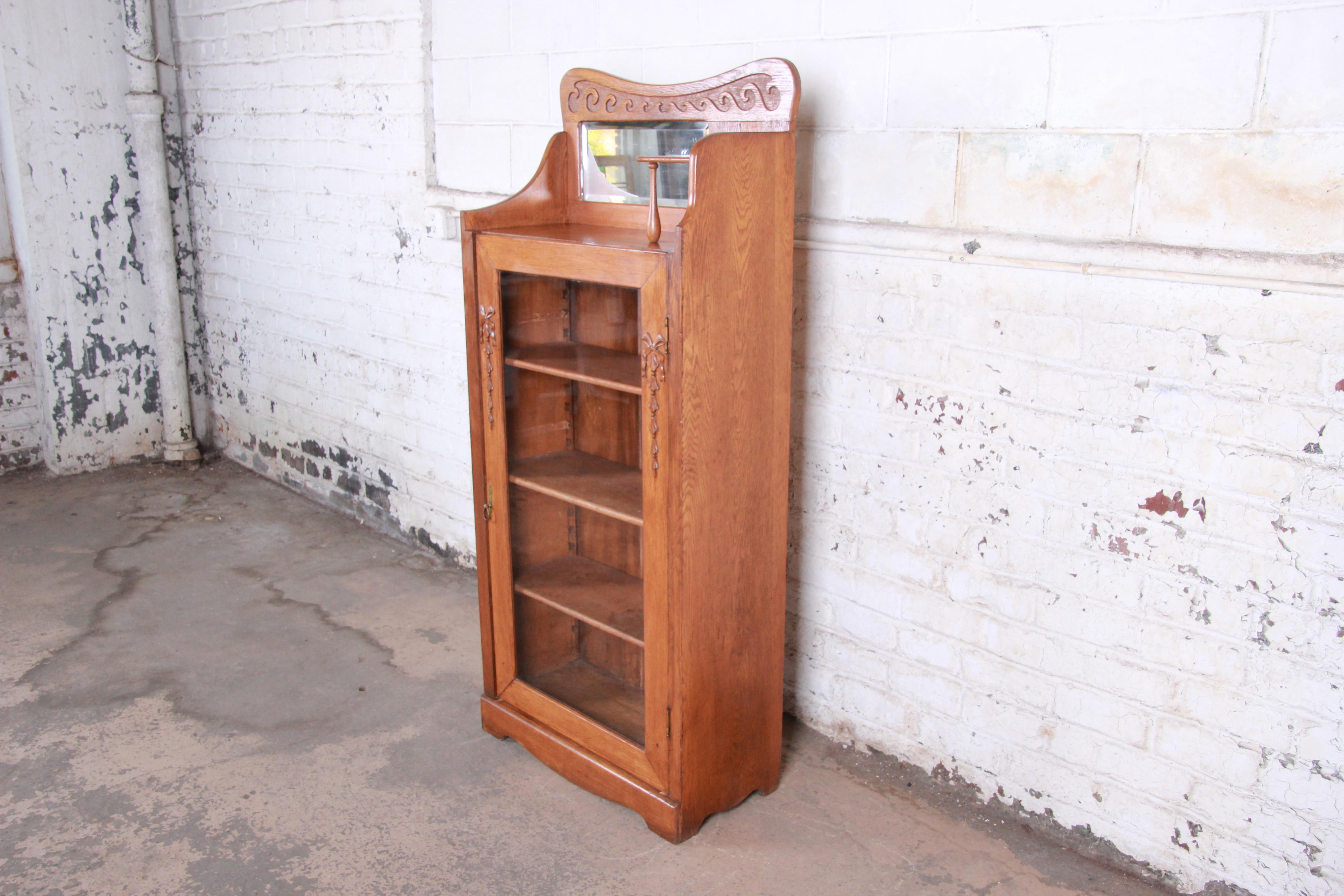 A gorgeous antique carved oak glass front bookcase, circa 1900. The bookcase features solid oak construction with beautiful wood grain and carved wood details. It offers good storage and display, with three adjustable shelves behind a single glass