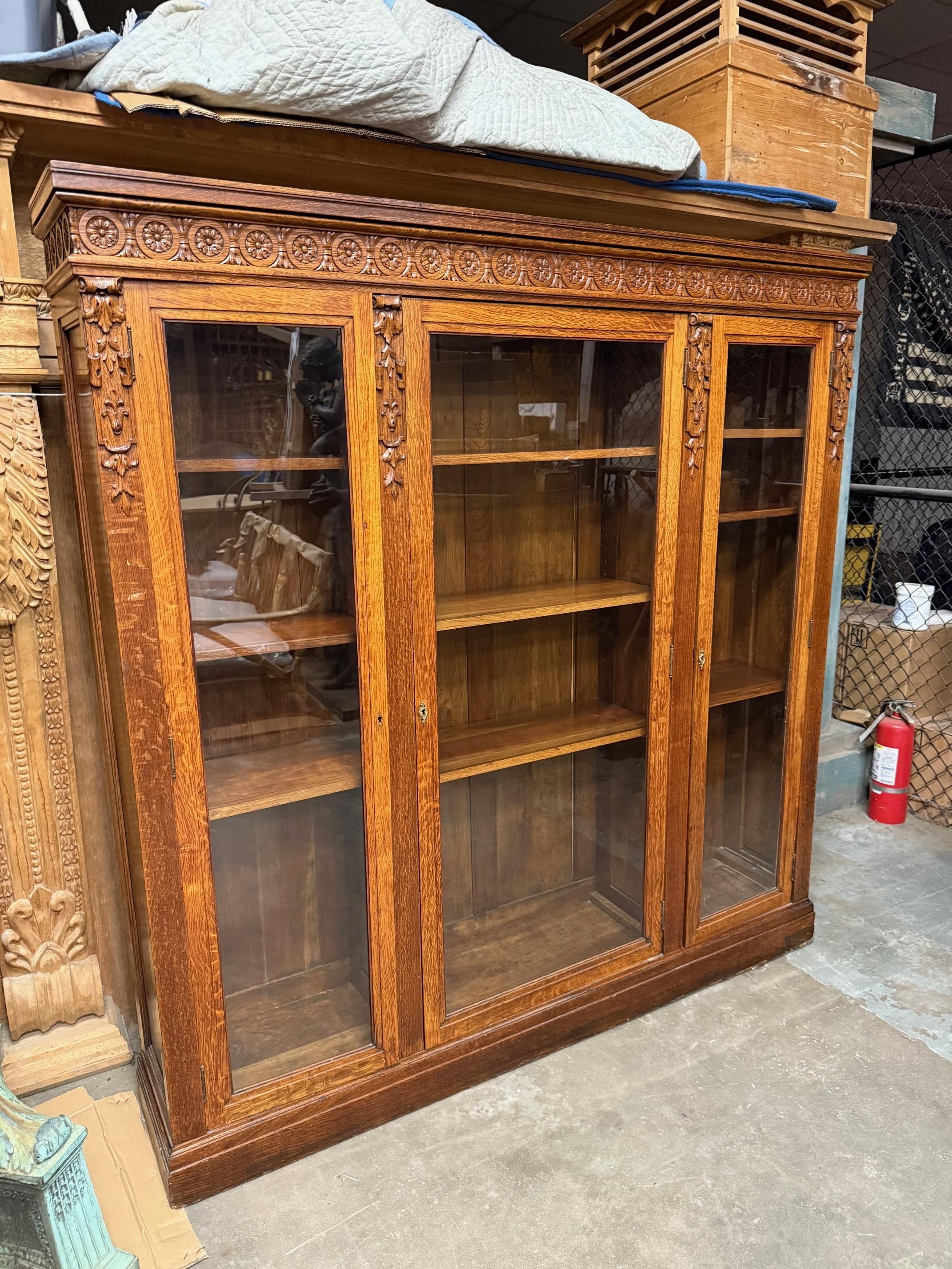Exceptionnelle bibliothèque en chêne sculpté de la fin du 19ème siècle et du début du 20ème siècle avec  triples portes en verre et étagères en bois. Il s'agit d'une superbe bibliothèque avec de magnifiques sculptures récupérées dans une propriété