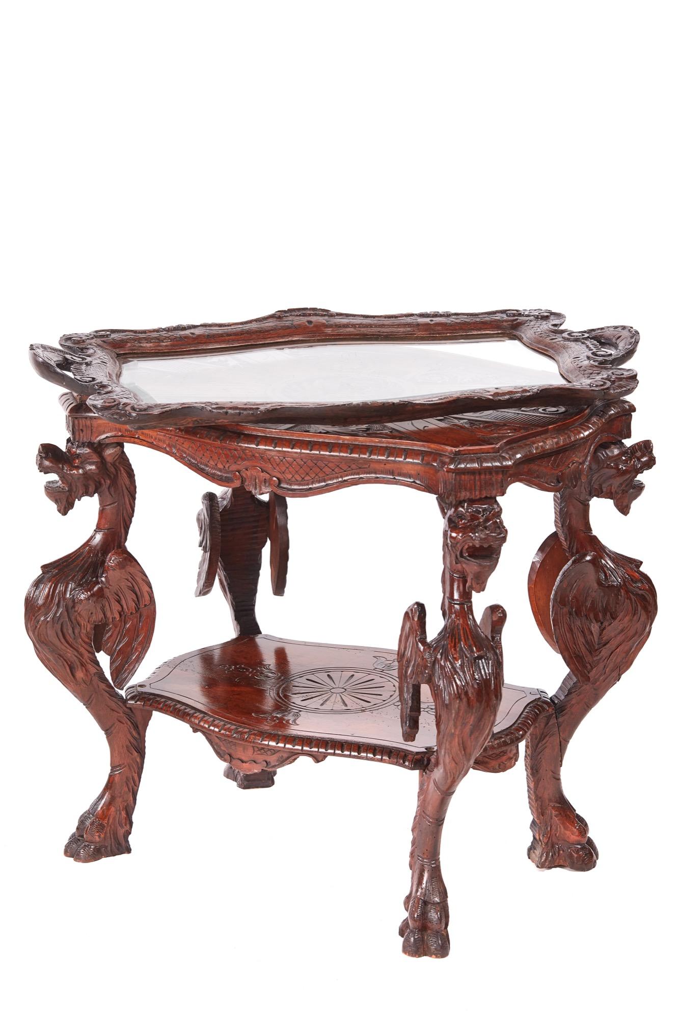 This is a splendid unusual antique carved oak Italian centre table having a serpentine carved top with lion decoration. It has a fitted removable tray with a glass top, the upper tier raised on four strikingly carved caryatid dragon legs on paw feet