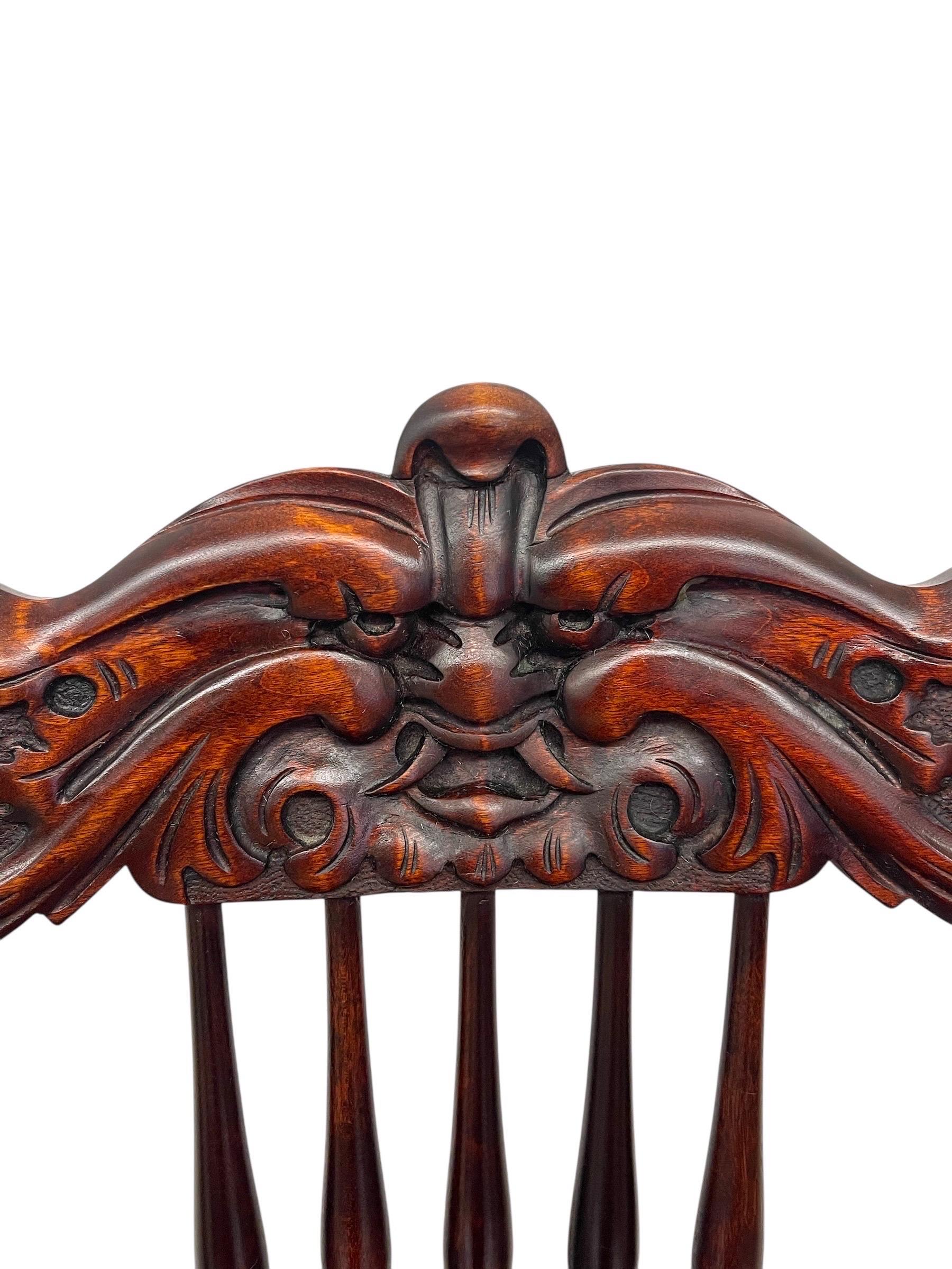 Ce fauteuil ancien en chêne est le fruit d'un travail de maître et d'une sculpture richement détaillée.

La traverse de l'écusson est ornée d'un masque 