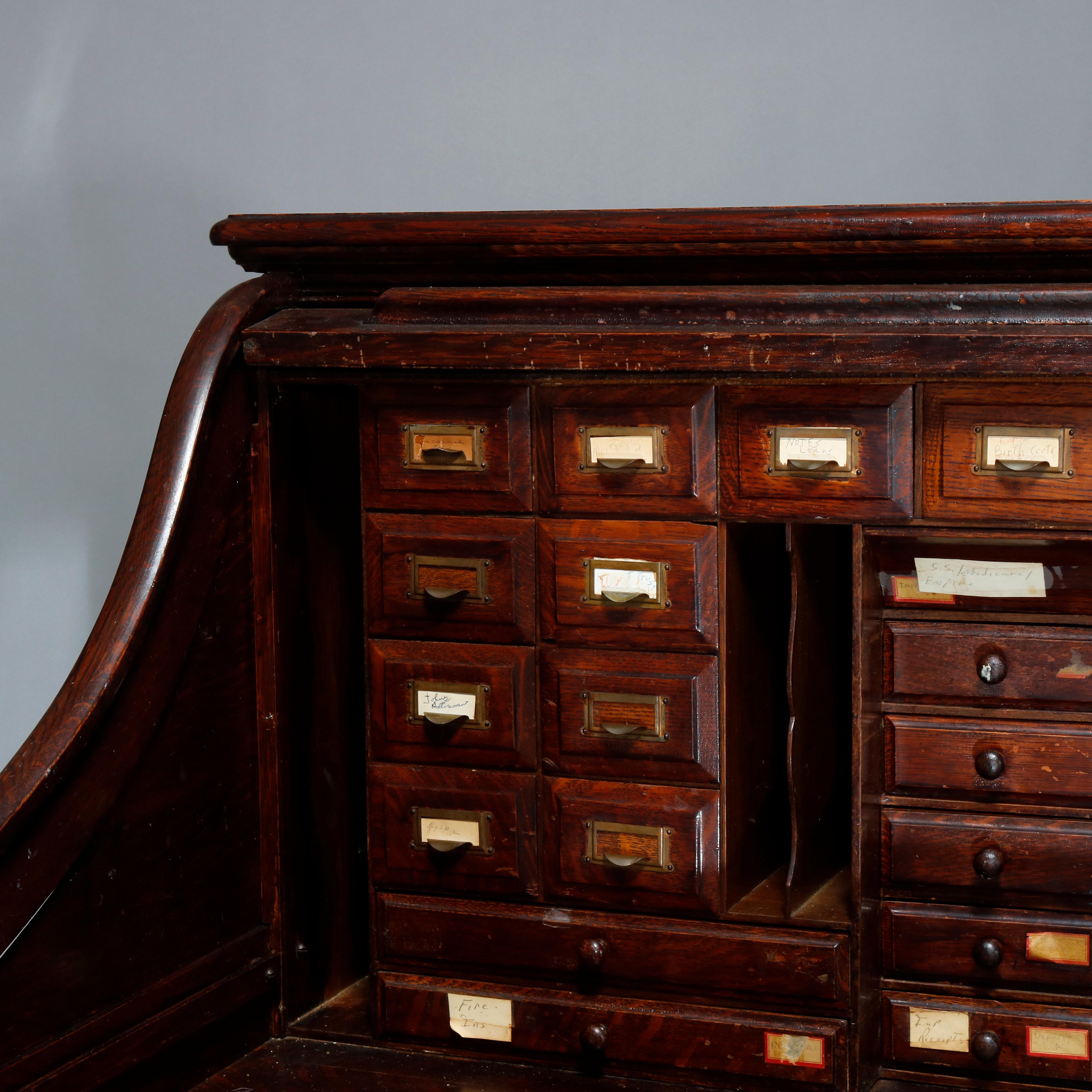 An antique desk by E.H. Staffordshire Bros. offers oak paneled construction with s-roll top opening to desk and storage surmounting frieze drawer and flanking drawer towers with carved pulls, signed E.H. Staffordshire Bros Chicago, circa