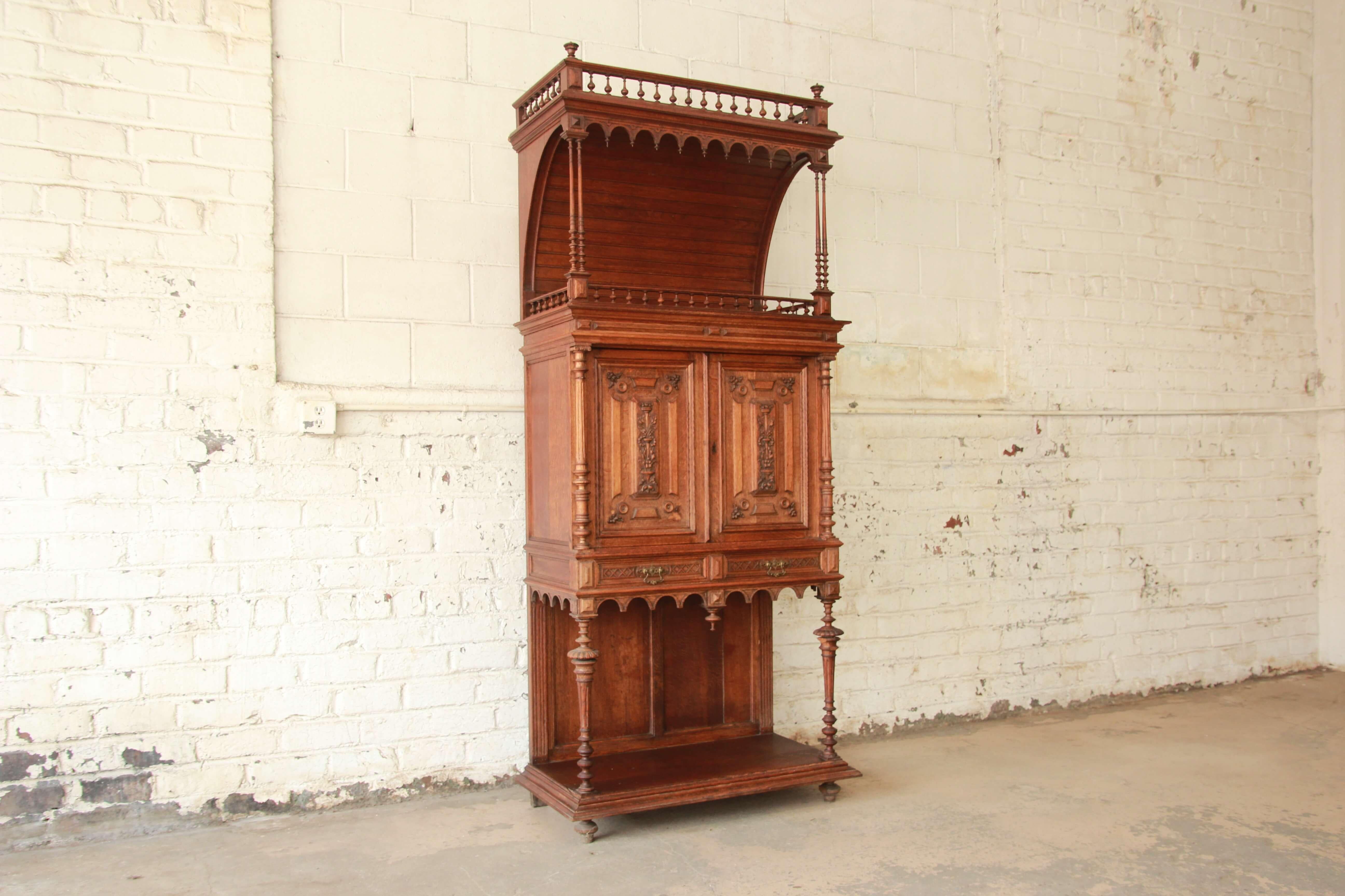 Offering a very nice antique carved oak tall French bar cabinet. This unique piece has beautiful carved details with multiple storage options for your liquor collection or books. Above is a unique shelf area with scrolled details and elegant French