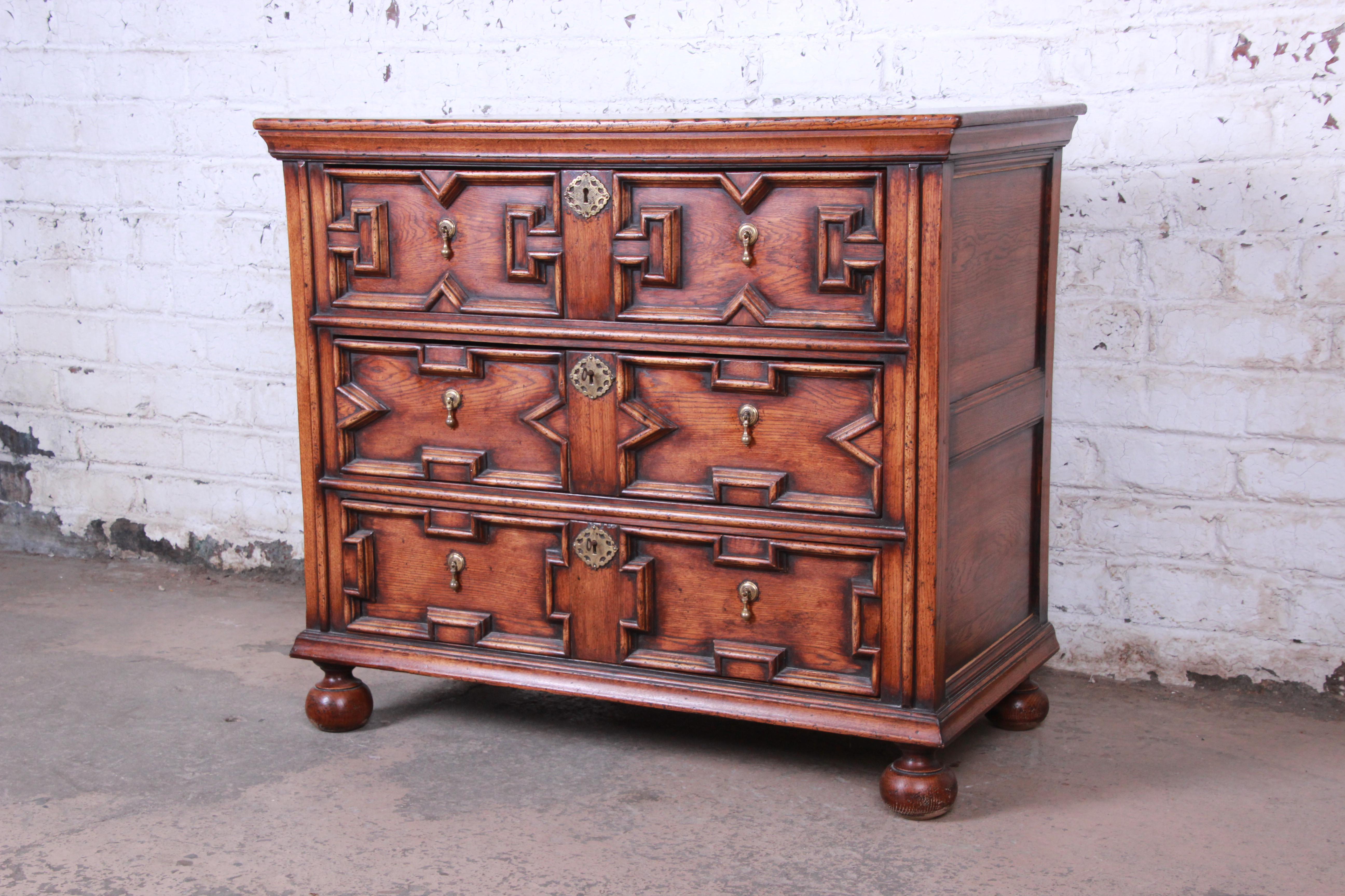 Offering a very nice and unique solid oak three drawer dresser or bachelor chest The chest has nice ornate carved details with three large sturdy drawers with tear drop brass pulls and decor. The bottom two drawers come with two locking keys. The