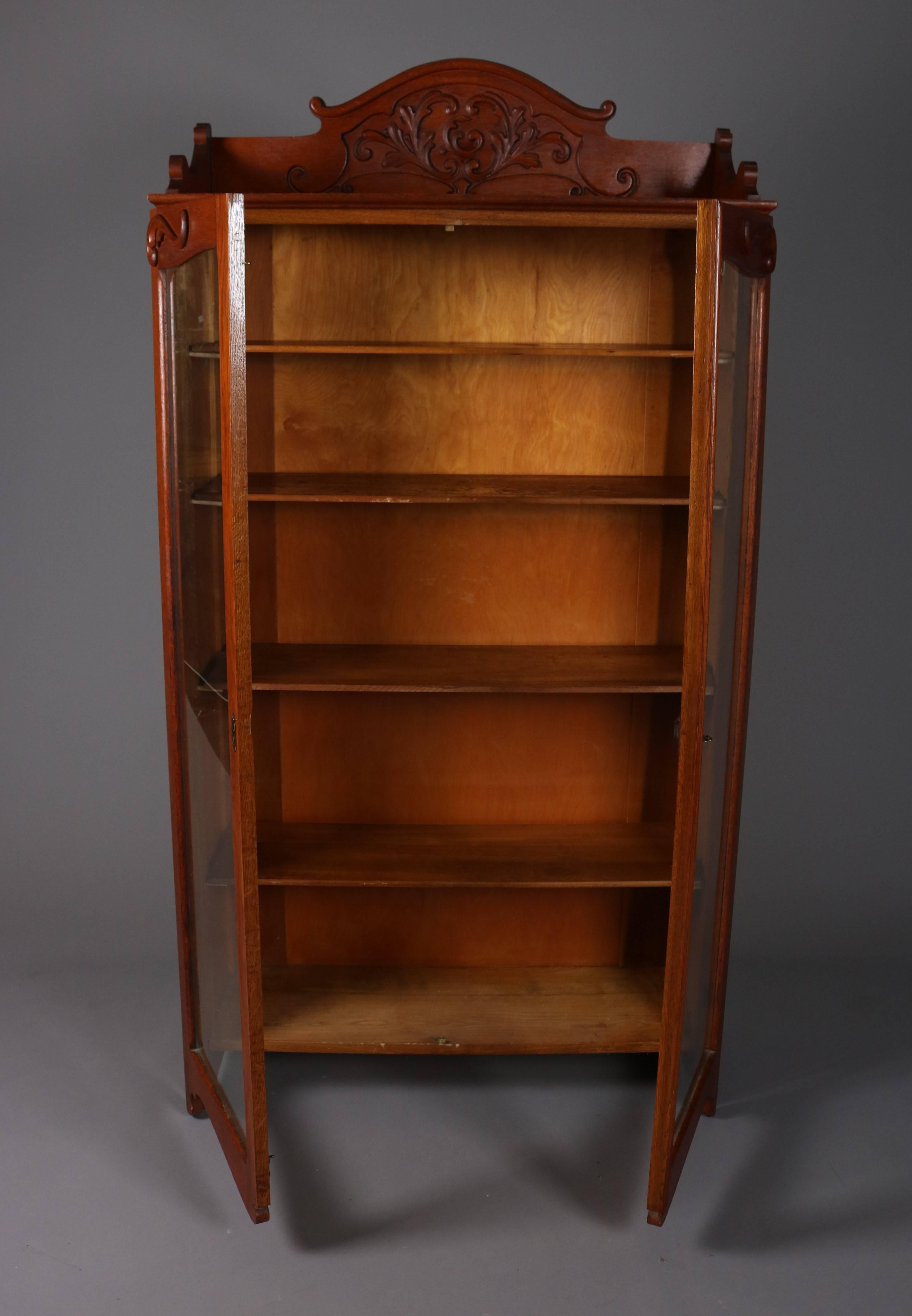 Antique oak bookcase features carved scroll and acanthus decoration, two glass doors, and adjustable interior shelving, 20th century

Measures: 71