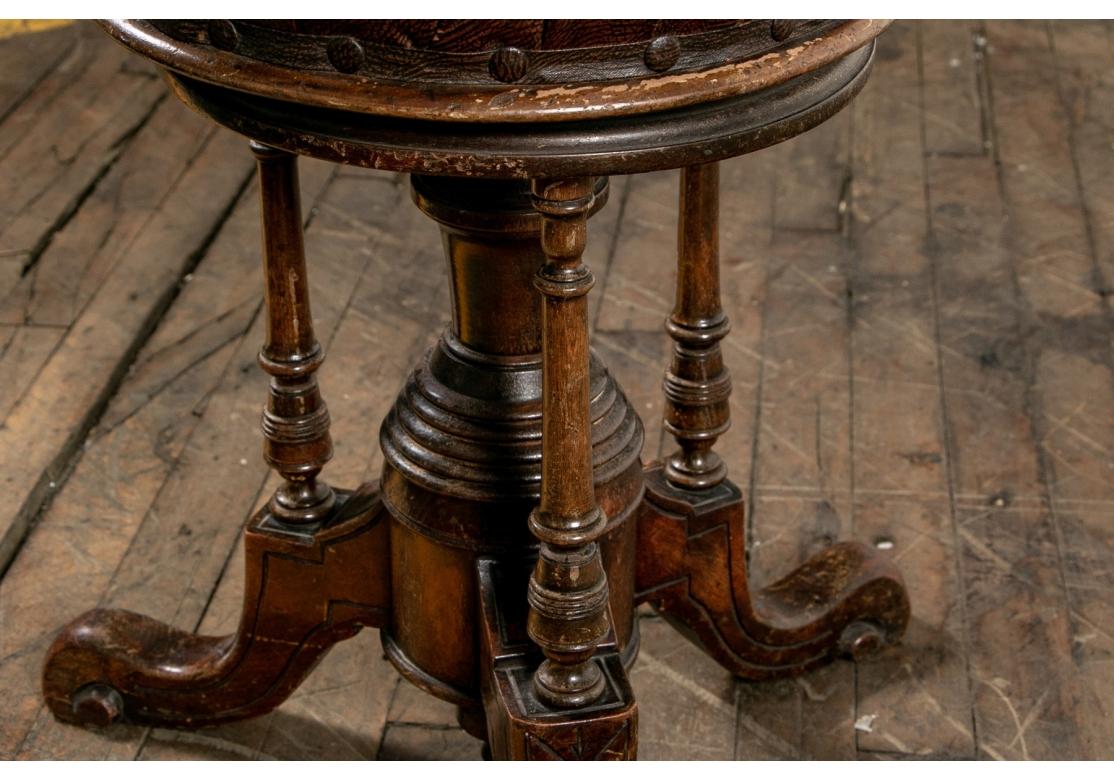 A rare and notable antique stool with brown leather seat, turned central support and supporting rods, bottom finial and adjustable screw action height. 
The stool measures 17.25” wide by 17.25” deep by 18.5” high.
Condition: Please see detail
