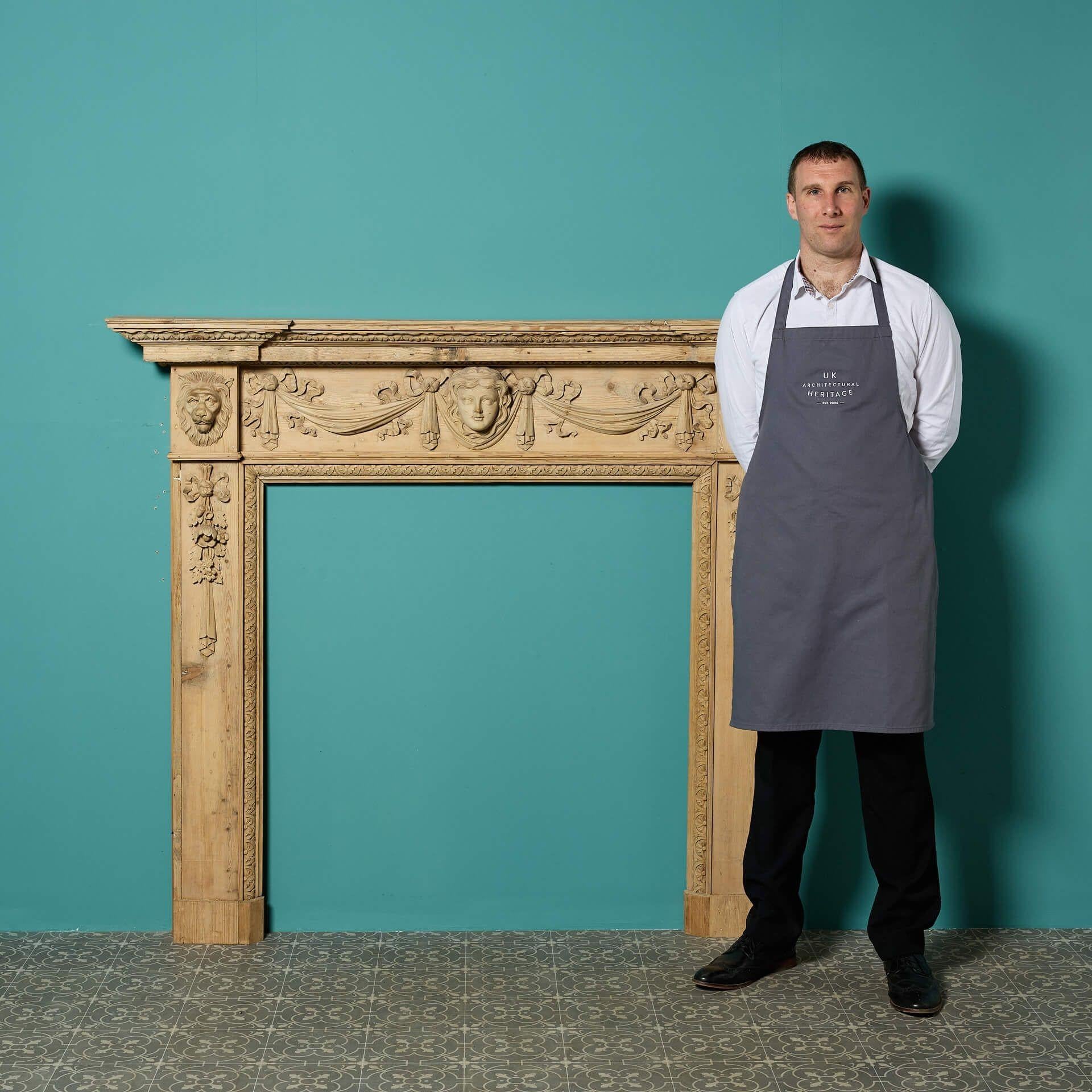 An antique carved pine fire mantel in the early Georgian / Palladian style of William Kent, the leading architect and designer of 18th century Britain.

Highly ornate, this large pine fire mantel is deeply carved with female mask and drapery to the