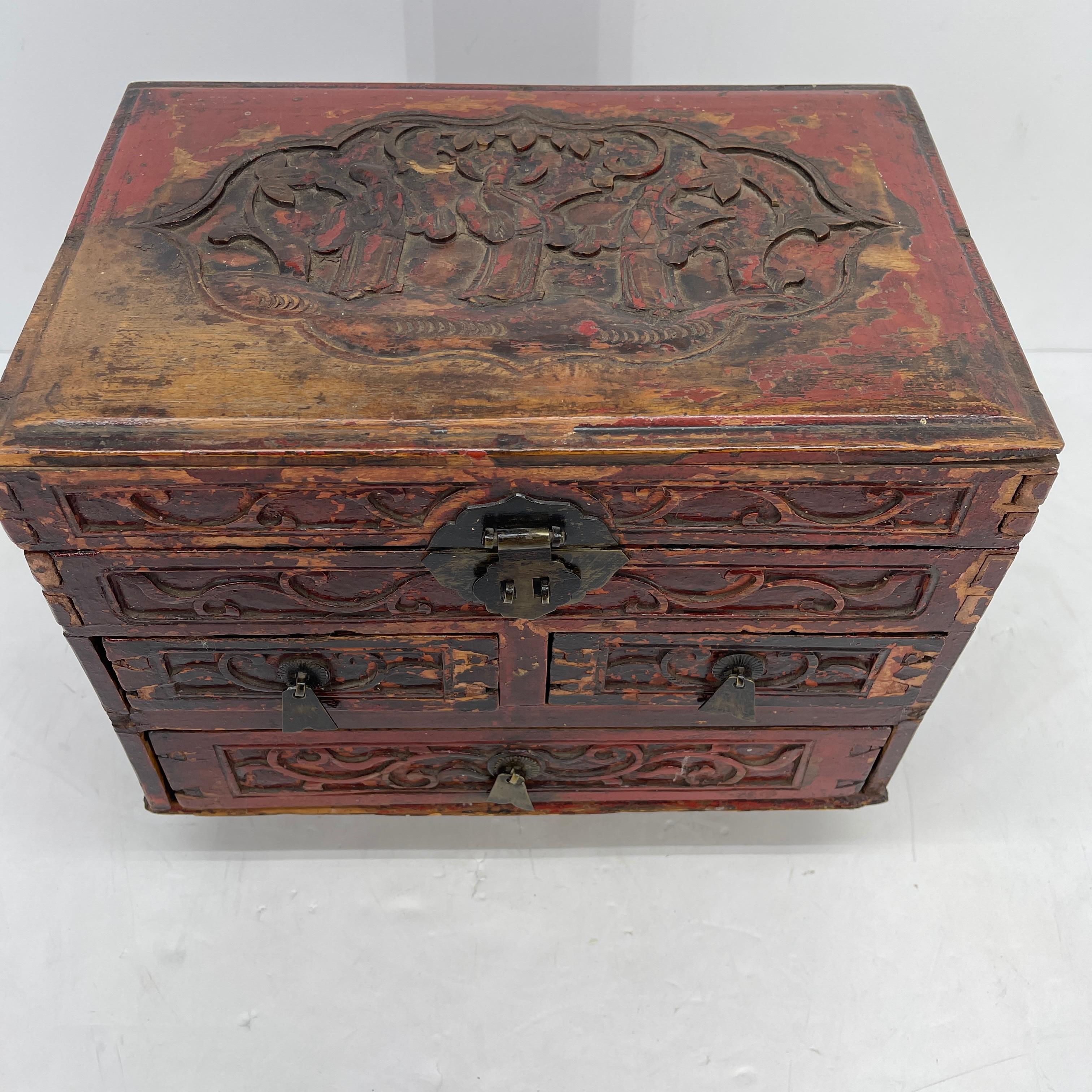 Antique Early 20th Century carved red brown lacquered wood and iron hardware jewelry box. This small Chinese rectangular box features a large bottom drawer, two smaller ones and a hinged lid. Having hidden wood locks inside to open and close all