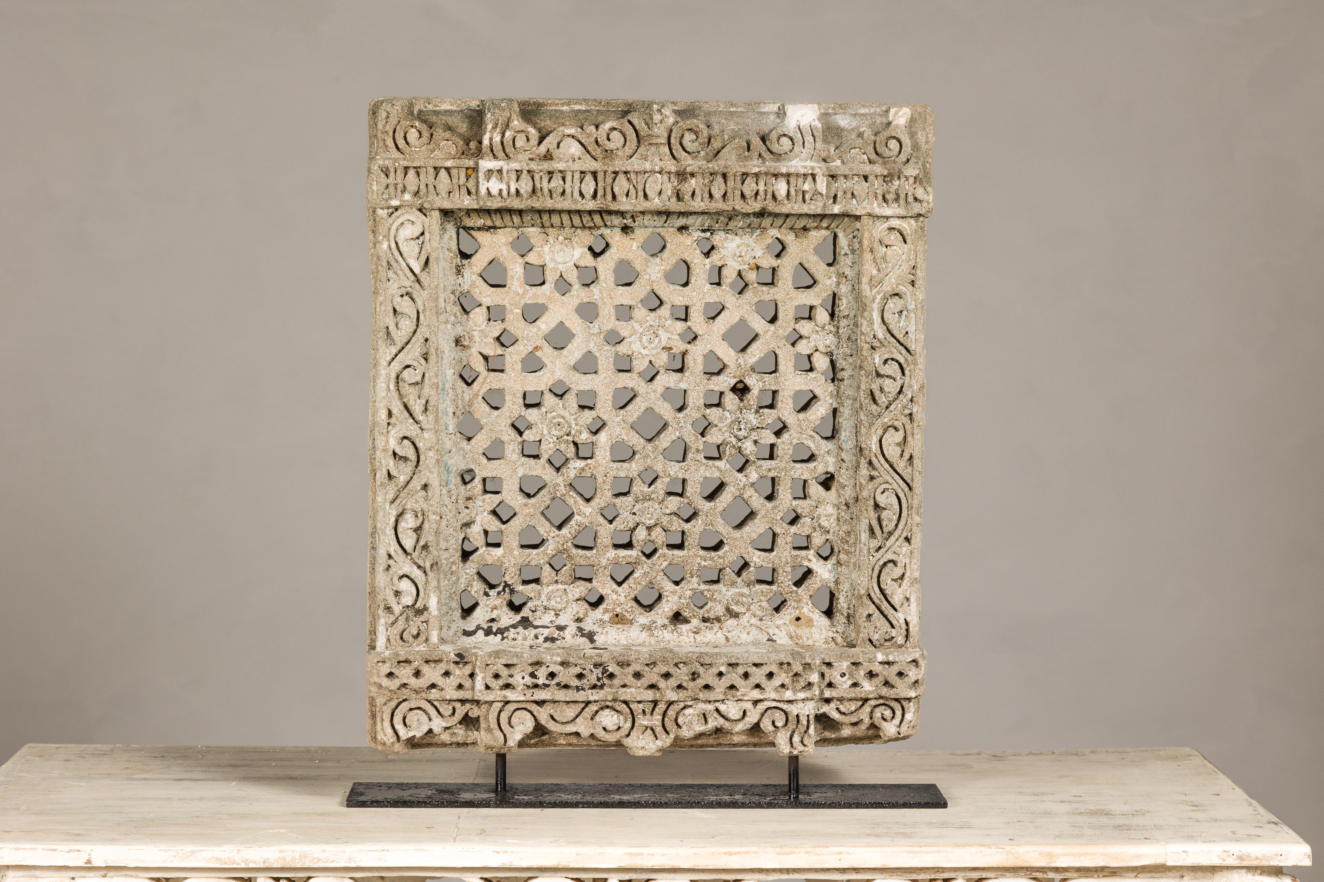 A small 19th century carved sandstone window sculpture from India mounted on a custom black base. Immersed in the rich tapestry of 19th-century Indian artistry, this carved sandstone window sculpture exudes historical allure. Emanating from an era