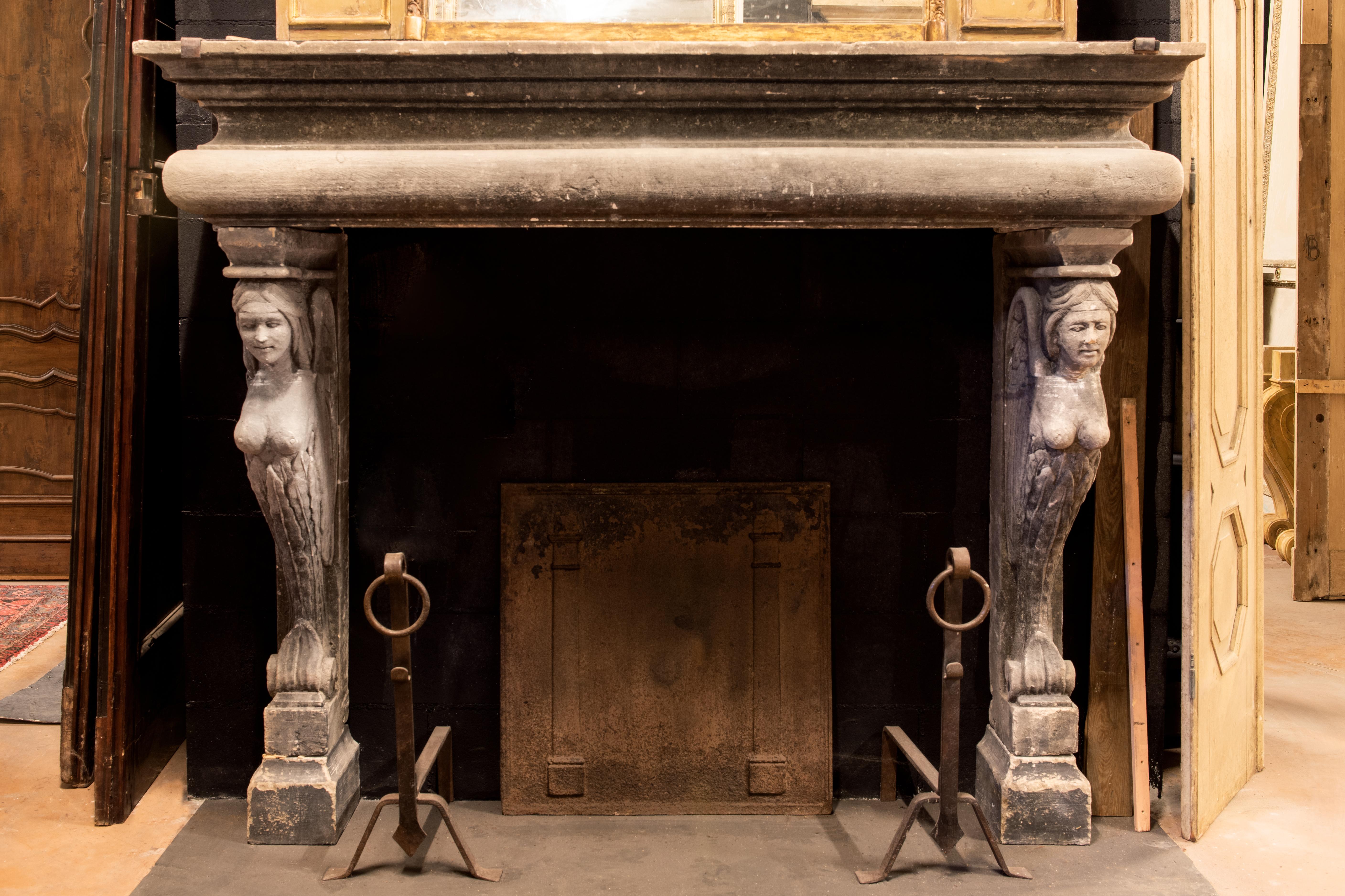 Ancient fireplace mantle in gray stone, hand carved with winged caryatids, shapely women and many more, large and rich, of sure scene in a large and refined environment.
It takes up the 16th century chimney, but was built in the 19th century in