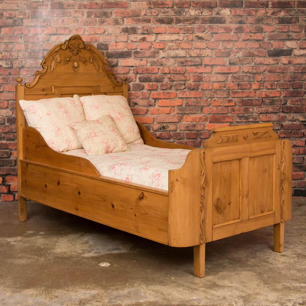 Enchanting antique pine single size bed from Sweden, circa 1850-1870. The headboard features beautifully carved crown moldings with large swags of carved flowers accenting the headboard and matching curved foot board. This bed fits a standard
