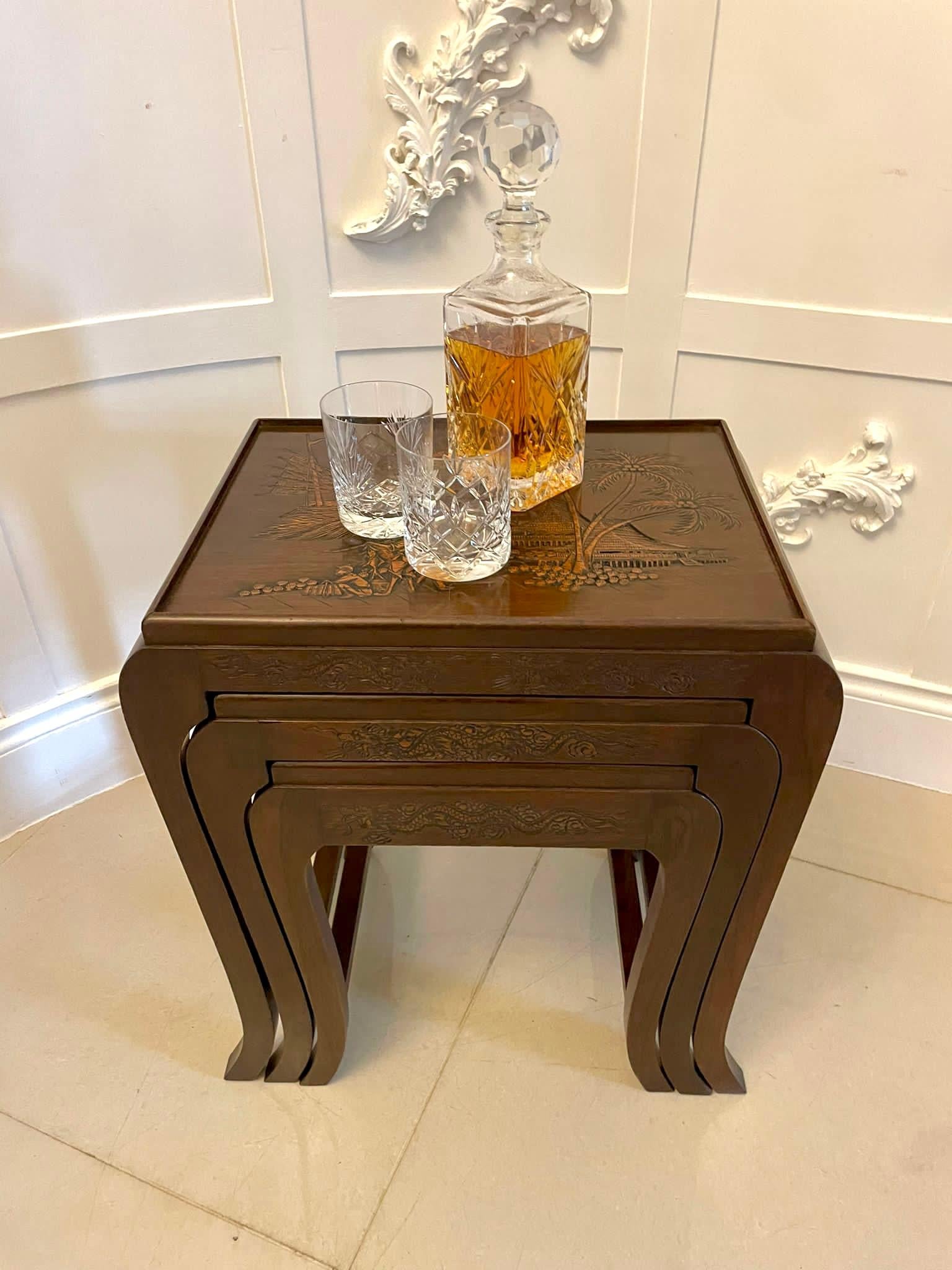 Antique carved hardwood nest of 3 tables all having quality carved tops depicting chinese warriors, a sailing ship, palm trees and a pagoda shaped house, they boast a shaped frieze standing on elegant shaped sabre legs united by square