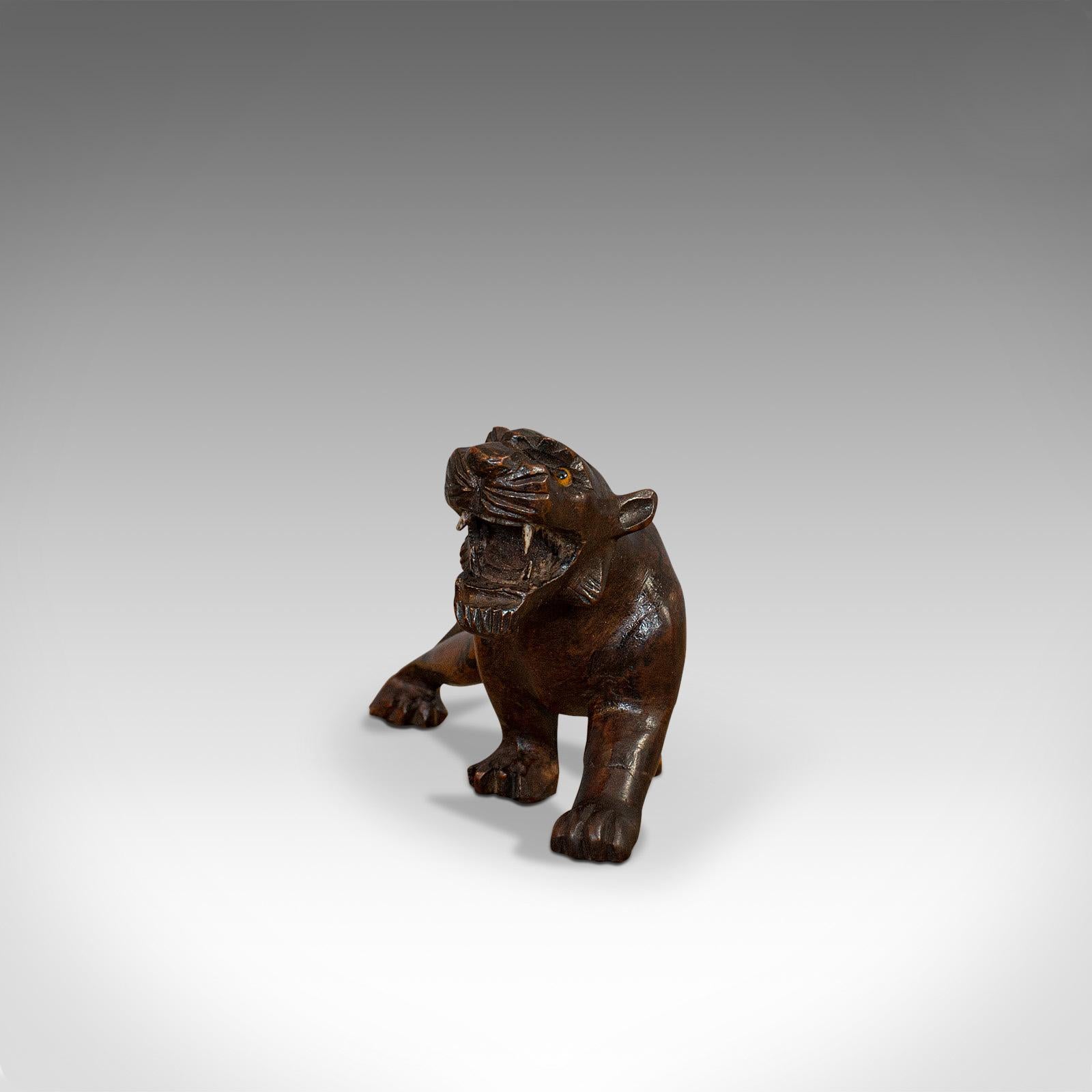 This is an antique carved tiger. An Asian, solid teak and bone decorative statue, dating to the early 20th century, circa 1920.

A prowling, handcrafted Panthera tigris
Displays a desirable aged patina
Skilfully carved solid teak captures the
