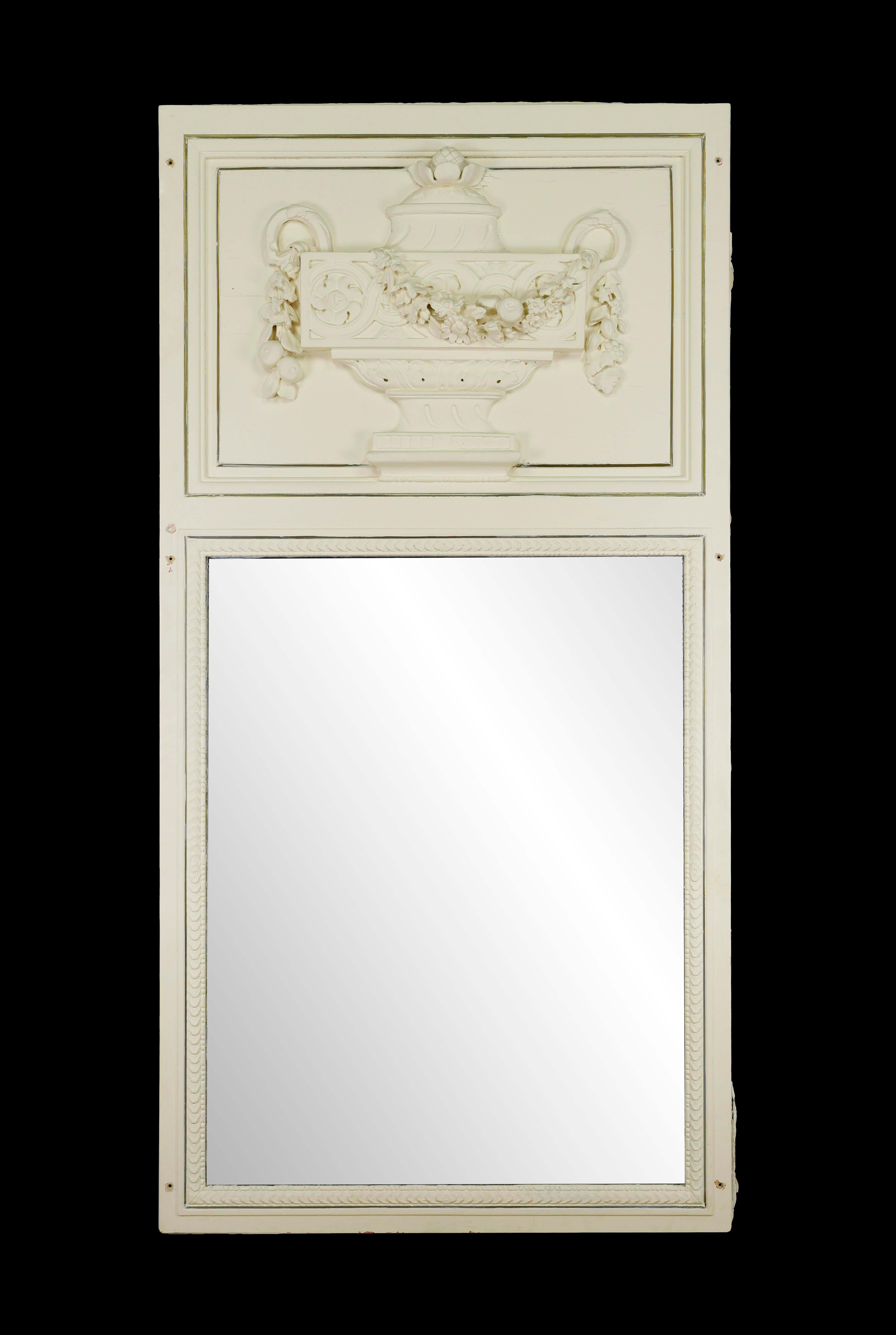 Fabriqué avec soin, ce miroir présente un cadre en bois blanc orné d'un magnifique motif d'urne sculpté. La bordure en laiton qui entoure le plâtre ajoute une touche de sophistication, soulignant les détails complexes. En très bon état, le miroir
