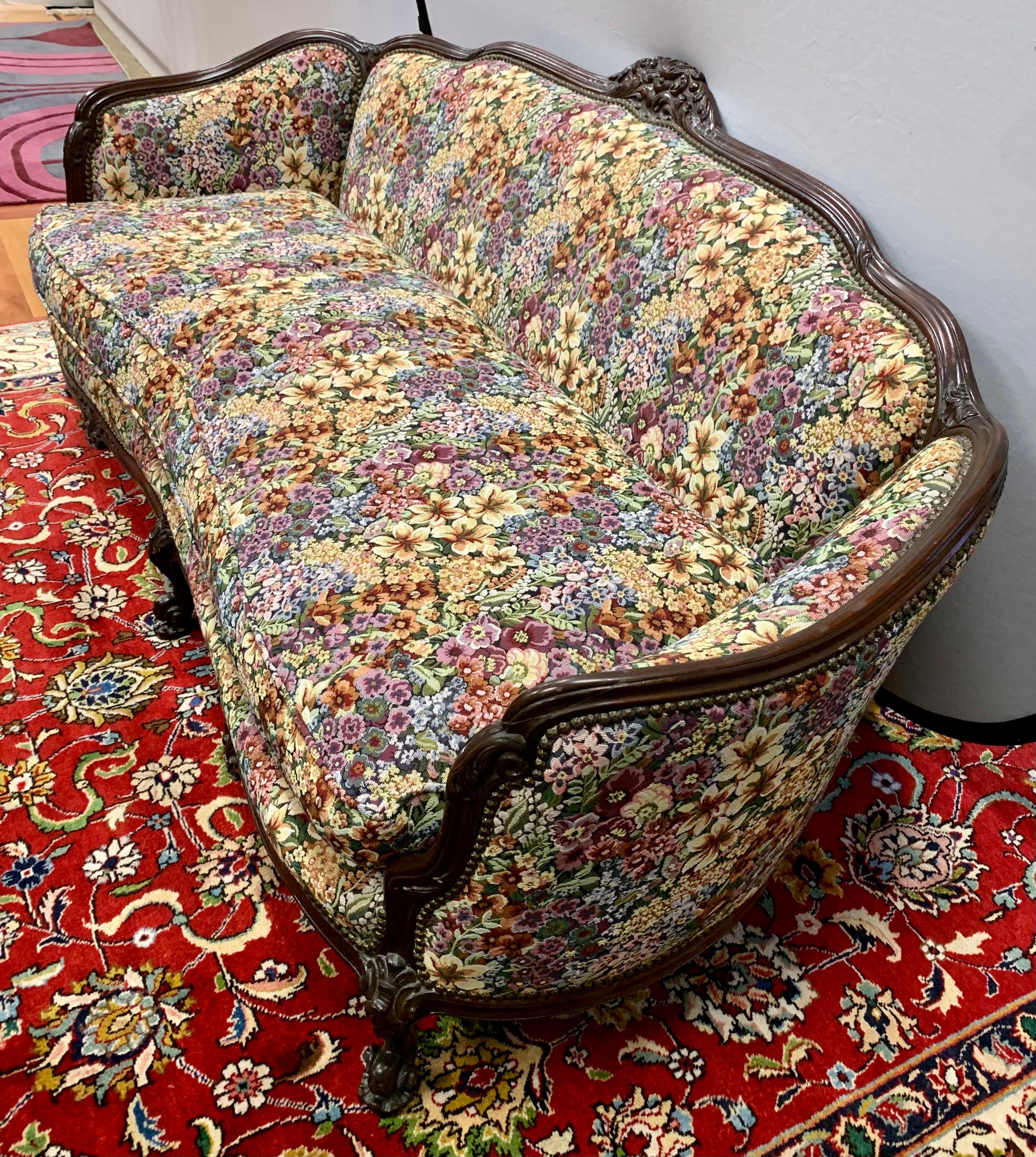 Extravagant carved Victorian sofa has been restored and reupholstered in a colorful tapestry fabric. Fabulous details include carved crest, scrolled arms and brass nailheads. Maximalism at its best!
