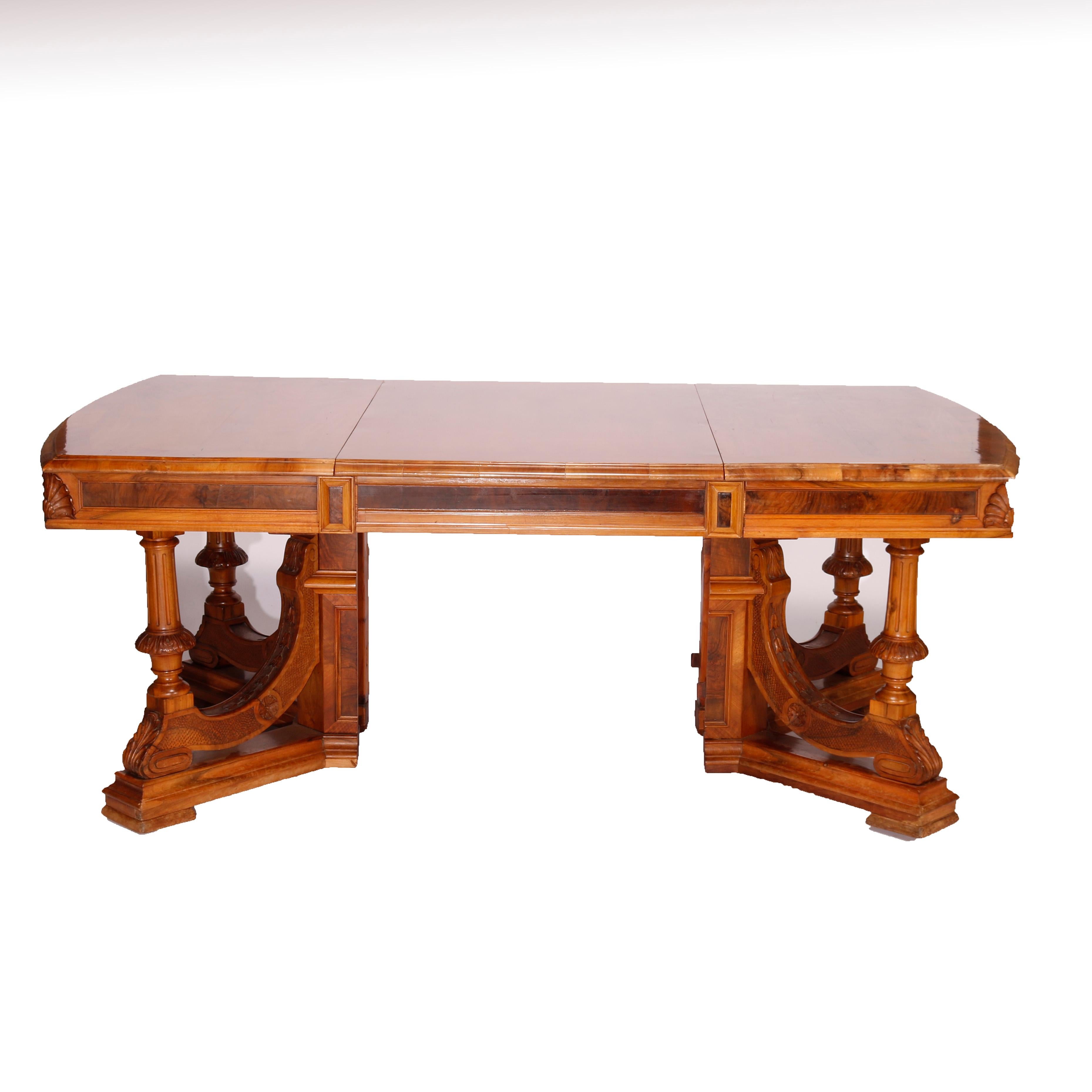 An antique extension dining or conference table offers walnut, burl and rosewood construction with shaped top having beveled edge and deep skirt, raised on carved balustrade legs seated on platform base, carved foliate and acanthus highlights