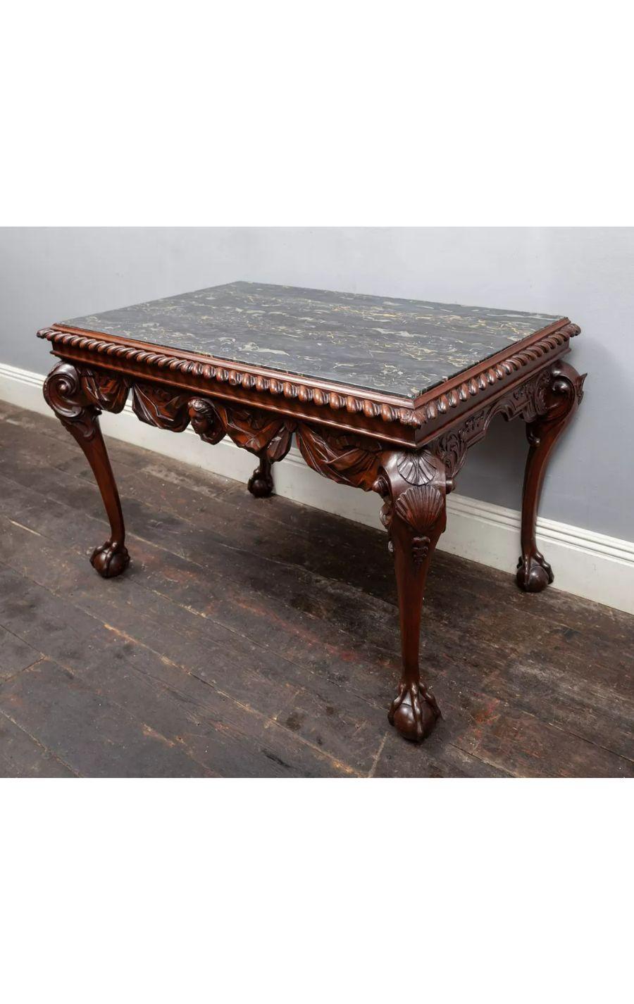 An antique carved Walnut console table with Portoro Nero marble top.

The frieze is beautifully carved with swags of drapes centred with a female mask. The canted legs with scallop shells carved on the knees, terminate with ball and claw feet. A