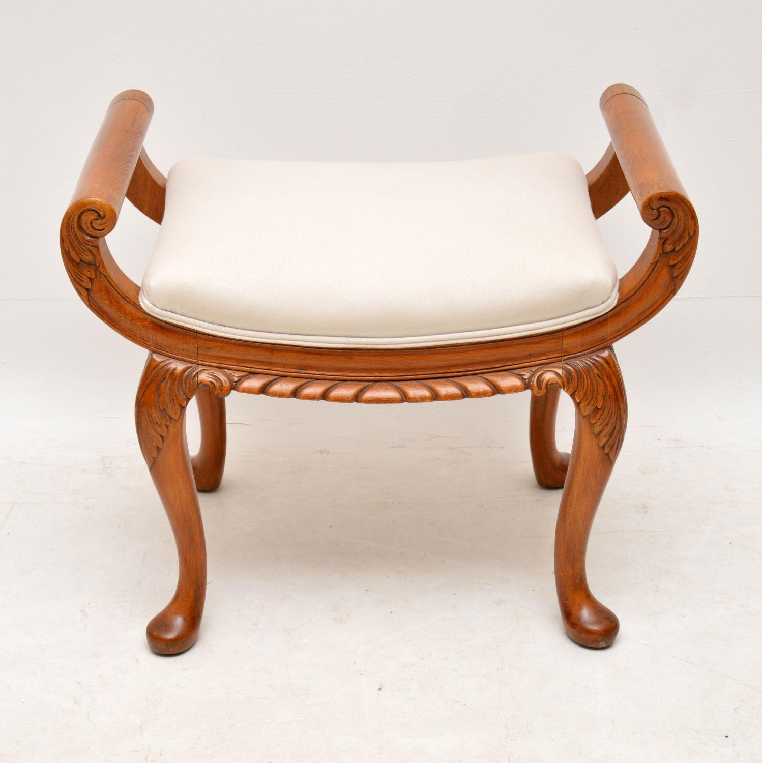 Antique walnut gondola shaped dressing table stool in excellent condition and dating from the 1920s-1930s period. It has deep carvings on the arms, between and on the legs. We have just had it French polished and re-upholstered in our regular cream