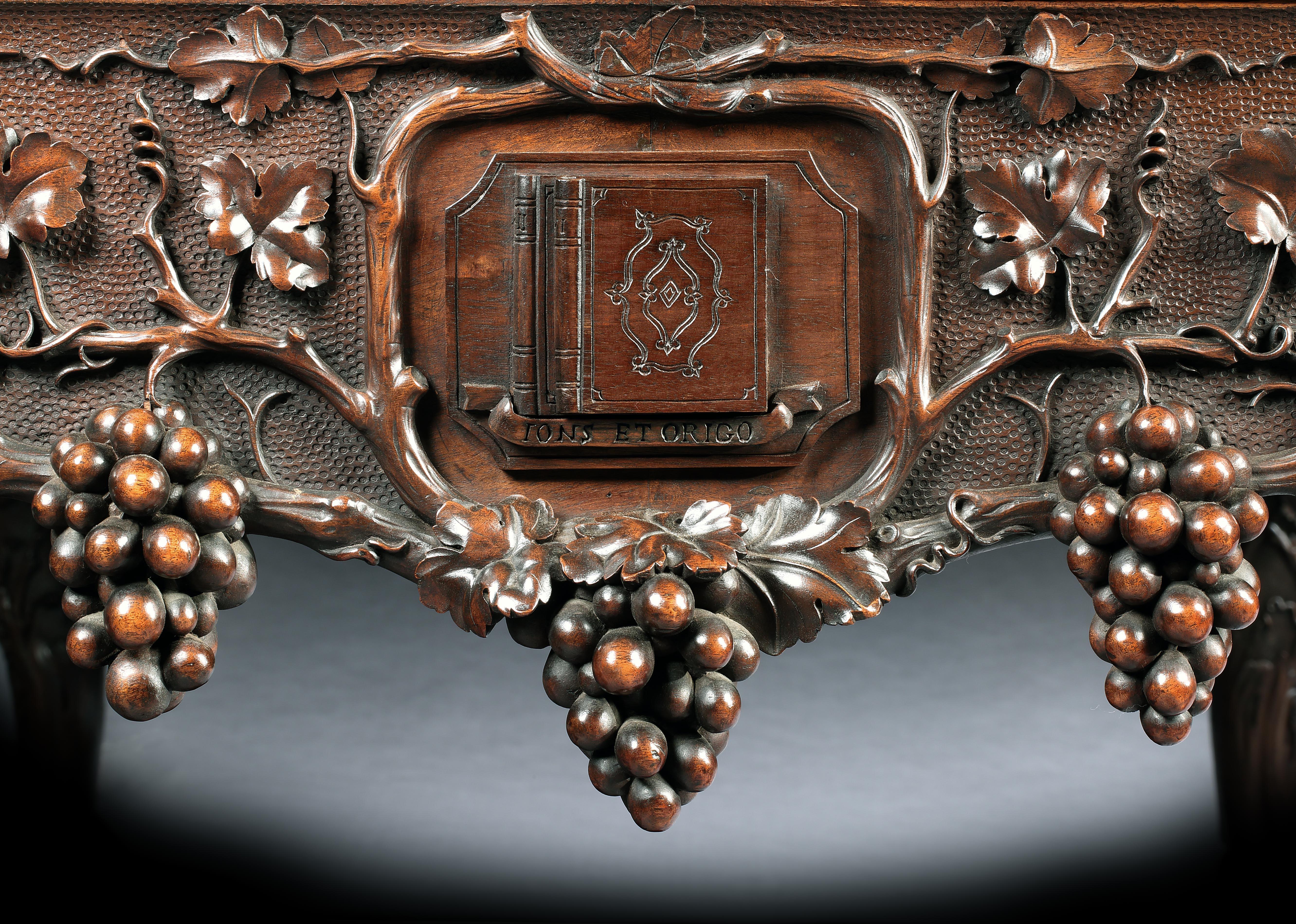 A carved walnut library table

Of grand proportions, the rectangular writing table rising from substantial cabriole legs terminating in firmly carved ball & paw feet. Having a tooled leather top set within an elaborate border incorporating carved