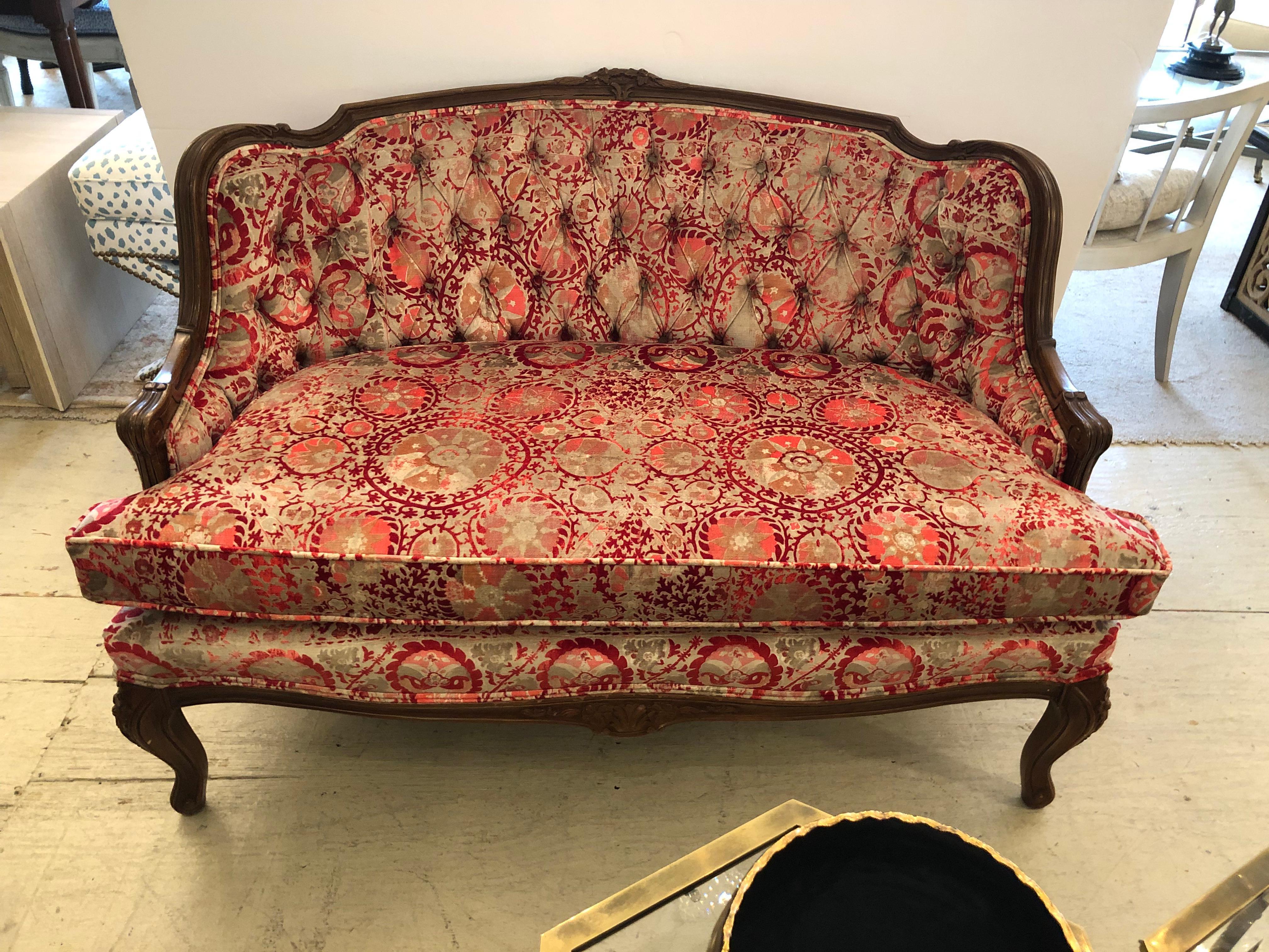 Charming diiminutive sumptuous French loveseat having richly patterned velvet upholstery in shades of rasberry and taupe. Frame is lovely carved walnut with short cabriole legs. The elegant tufted back has double welting, and from the back it curves