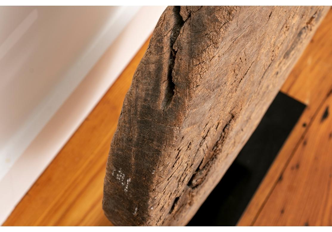 A weathered hand crafted antique wooden wheel (Likely of Asian origin) with rectangular center opening mounted as Sculpture on a black painted stand.

Dimensions: H. 25