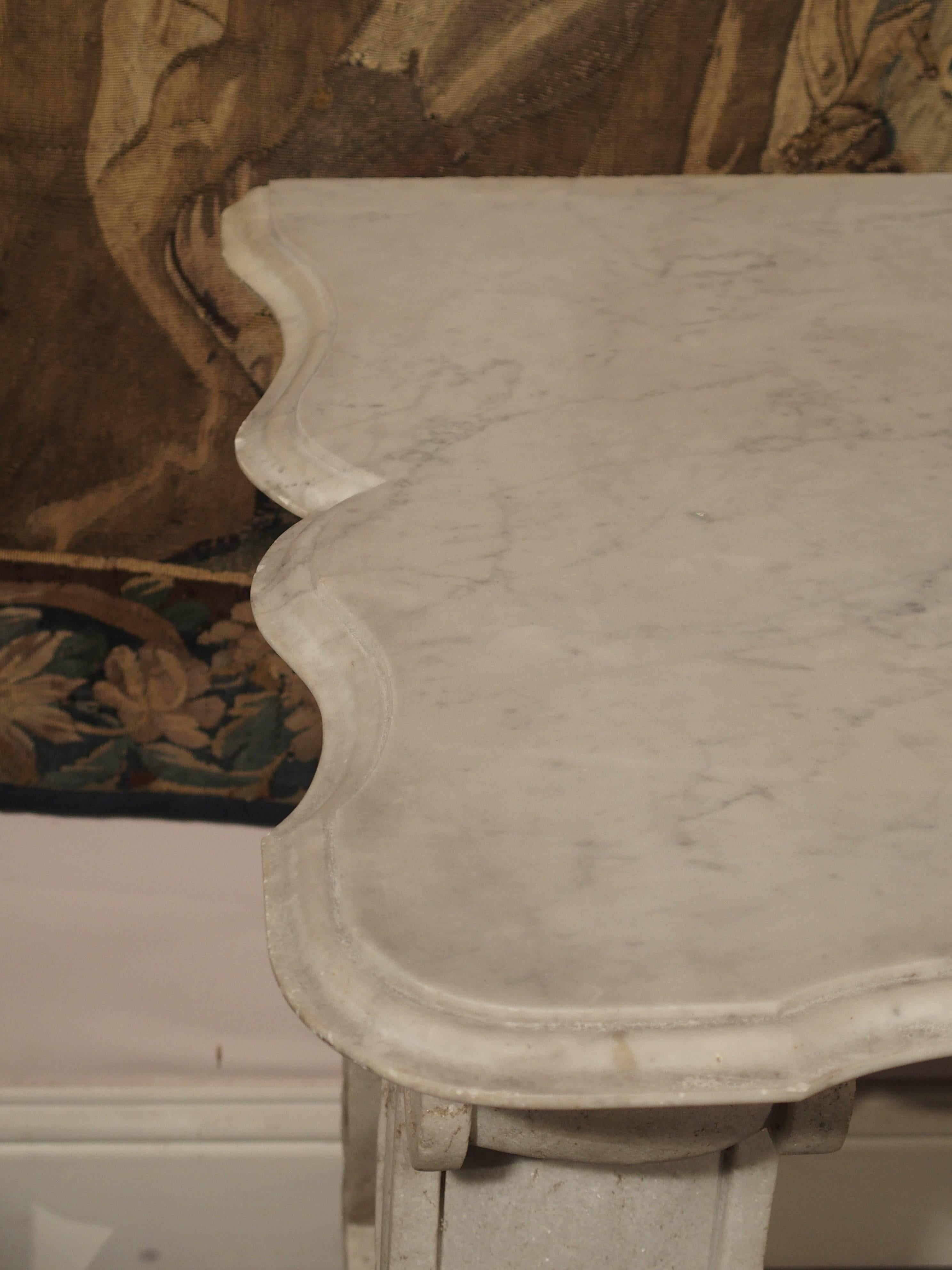 From France, this beautiful antique white marble console has flecks of gray throughout, and dates to the 1800s. It is a true console table in that it has a shaped top on the front and sides with a flat back. Lyre shaped legs, starting and ending in
