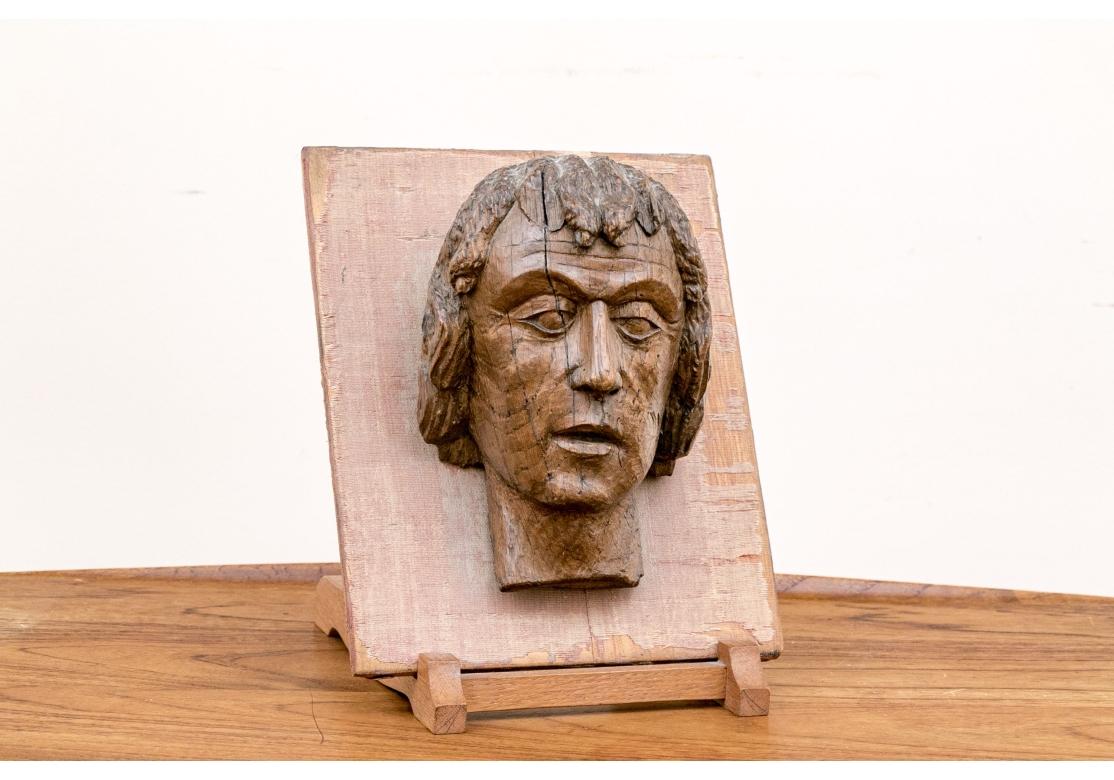 A well carved hardwood bust reminiscent of sacred and religious sculpture of the Gothic and Renaissance eras.  Antique carved wood head of a male mounted on a rectangular board and accompanied by a wood easel stand.

Dimensions: 10