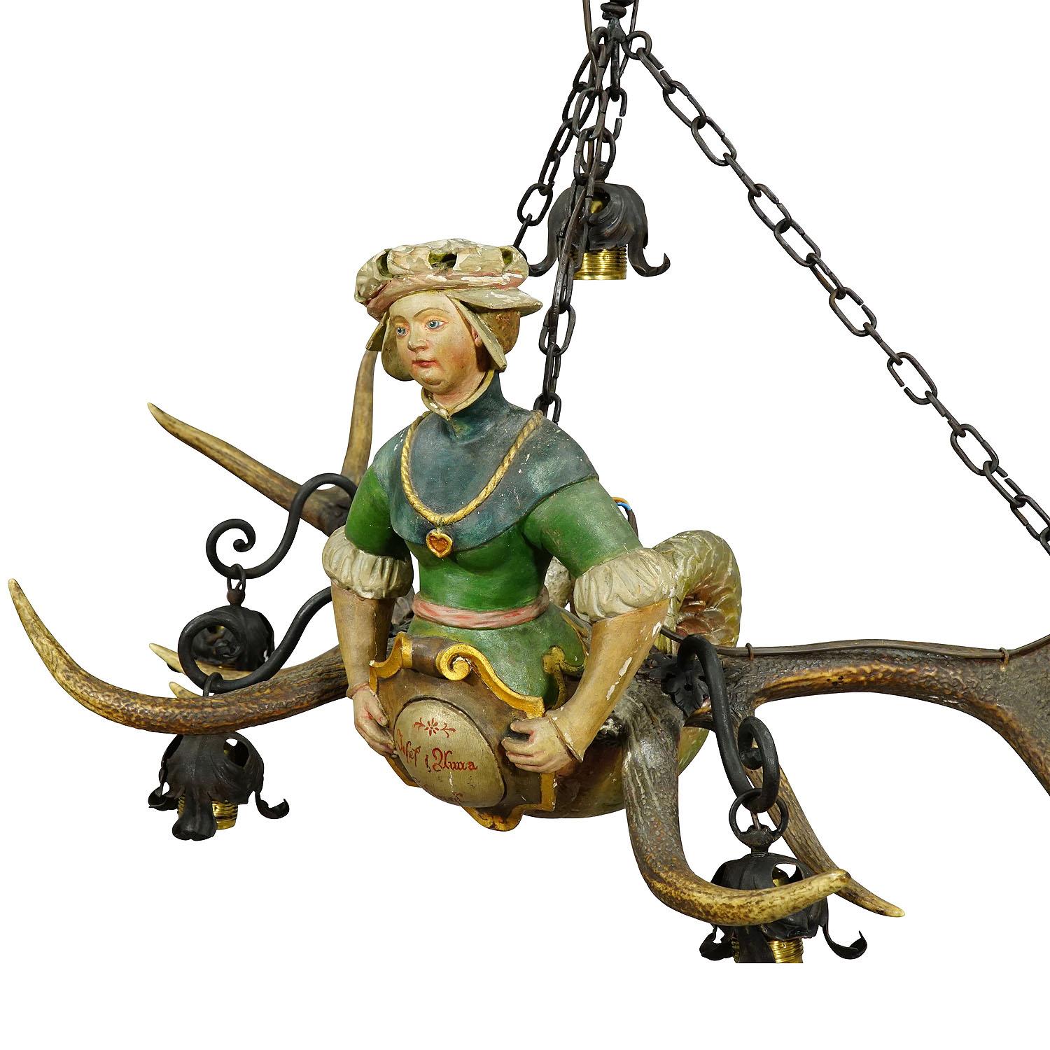 Item e6184
A wooden hand carved and painted statue of a two tailed meermaid representing a medieval lady. Fixed on a large pair of original deer antlers. Named lusterweibchen or lüsterweibchen, executed circa 1890. With hand forged iron suspension