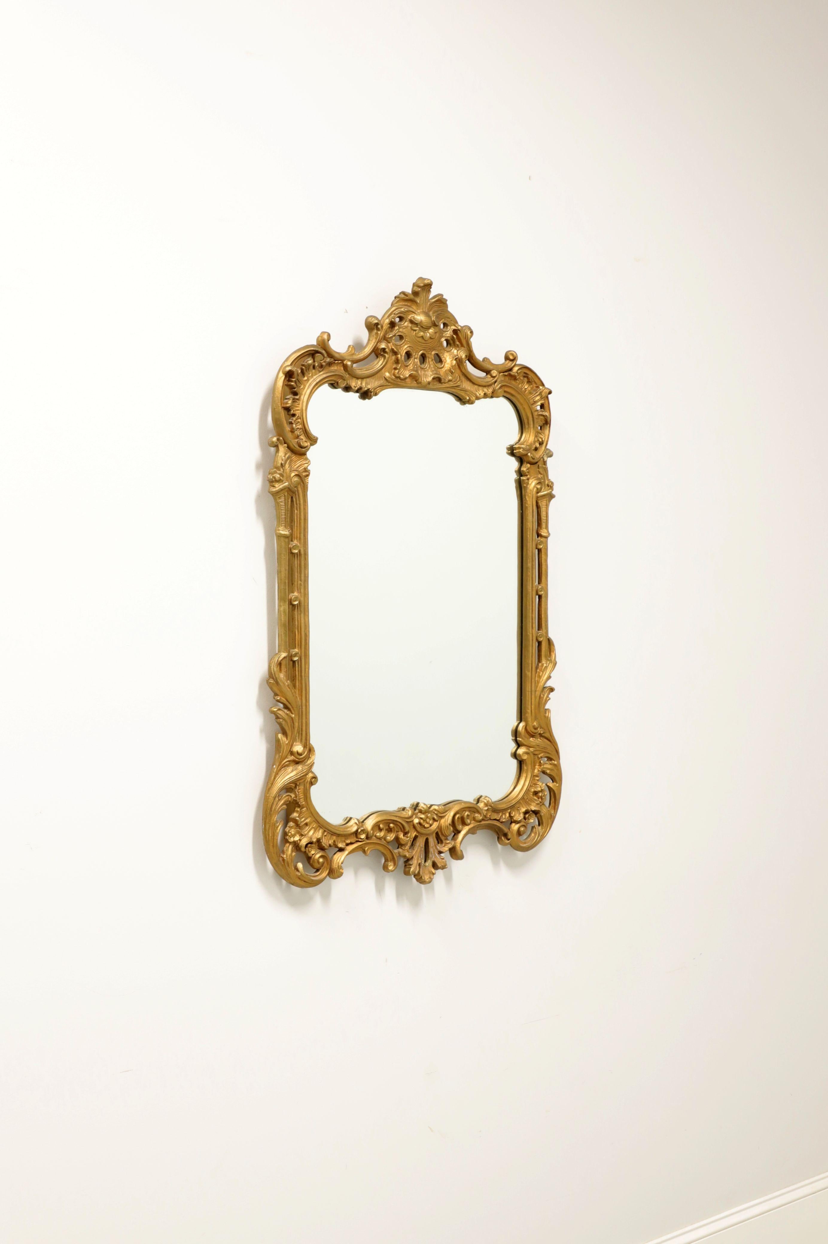 An antique Regency style wall mirror, unbranded. Mirrored glass in a wood frame painted gold. Features an ornately carved frame with a decorative motif. Possibly made in USA, in the late 19th Century.

Measures: 26.75W 1.5D 41.5H, Weighs