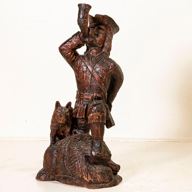 This antique oak sculpture shows off old world craftsmanship in the hunter, dog and bear. Review the close up photos to appreciate the hand-carved details in the hunter's hat, horn, belt, and rifle slung around his shoulder. Age related cracks are