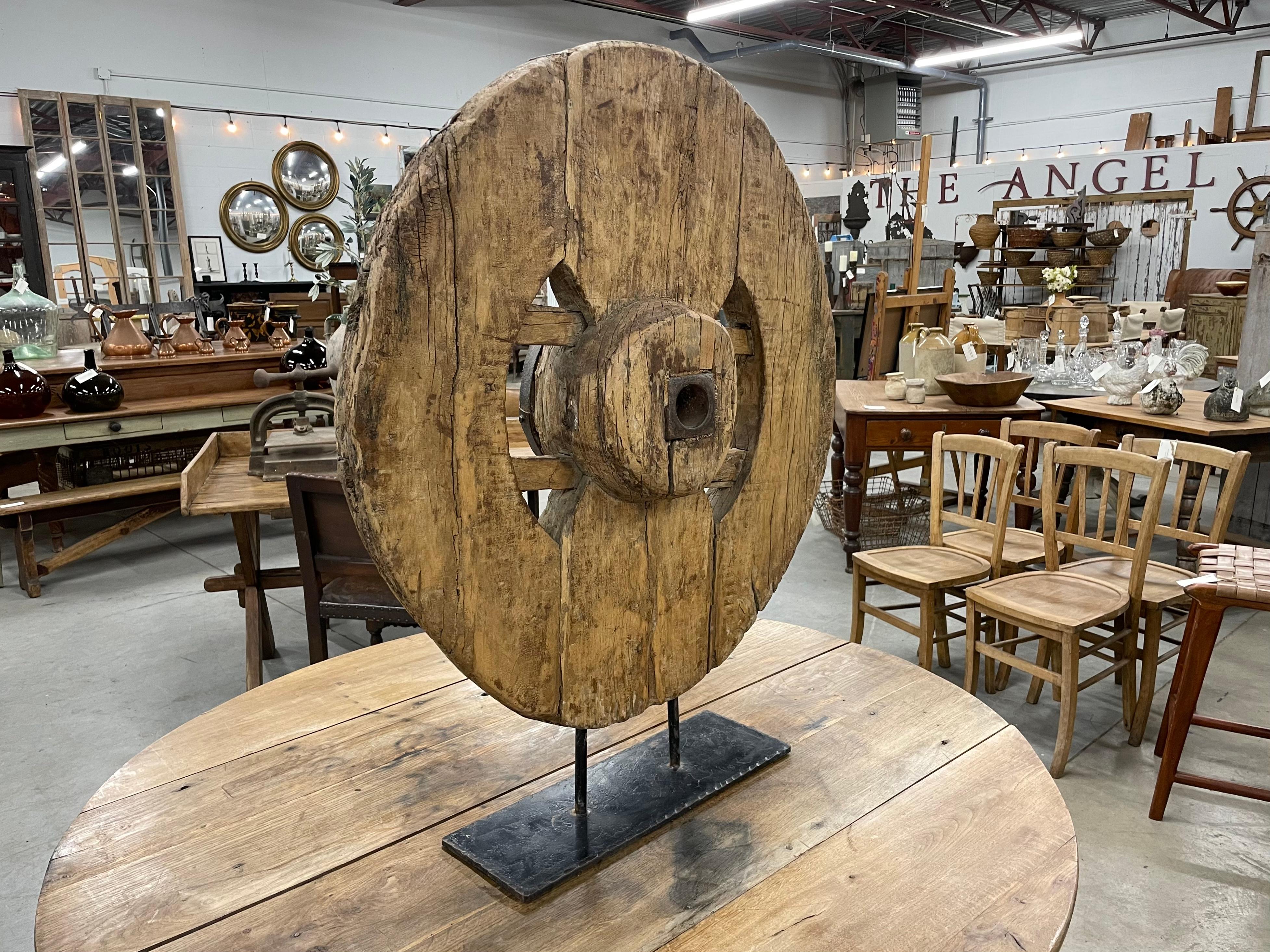 Substantielle roue antique en bois sculpté sur un support en fer. Merveilleux objet de décoration primitive.