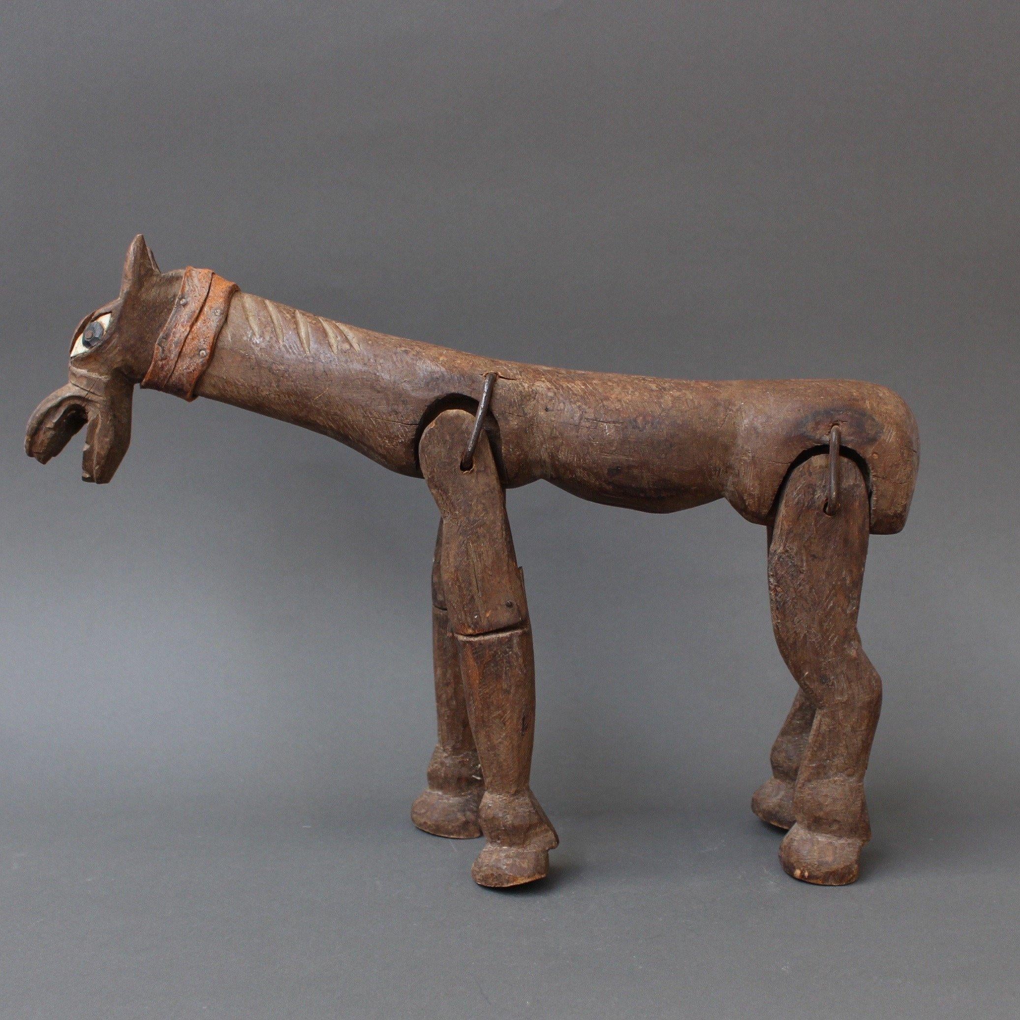 Antique, hand-carved wooden horse marionette in folk art or primitive style, circa 1800s, probably French. The legs are attached to the body with pieces of iron enabling their movement for puppet shows. This is a unique piece and is completely