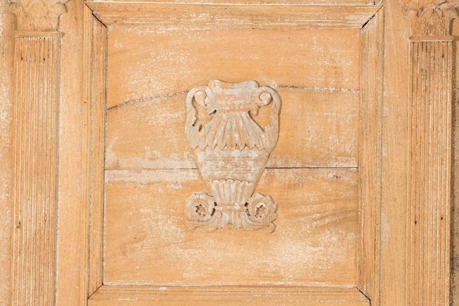 Wonderful grand scale antique wooden trumeau mirror. The aged white washed wood has a mellowed patina and is decorated with carved Corinthian columns finished on a plinth base, and a carved urn detail in the center as a lovely focal point.