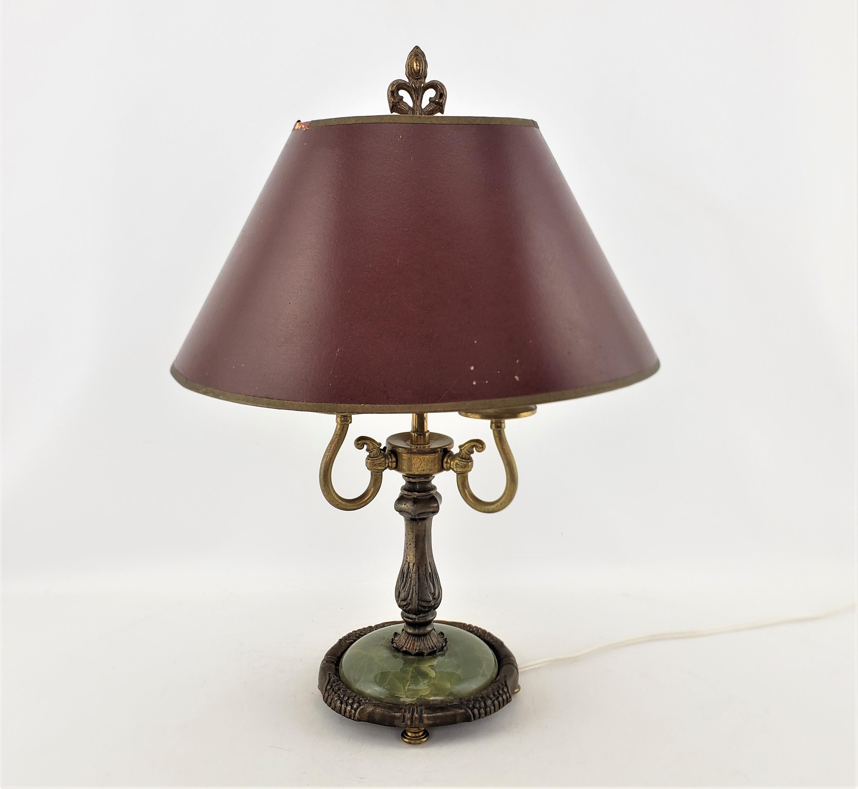 This antique bouilette style desk or table lamp is unsigned, but presumed to have originated from England and date to approximately 1920 and done in the French Empire revival style. The lamp is composed of cast brass with a fleur de lis stylized