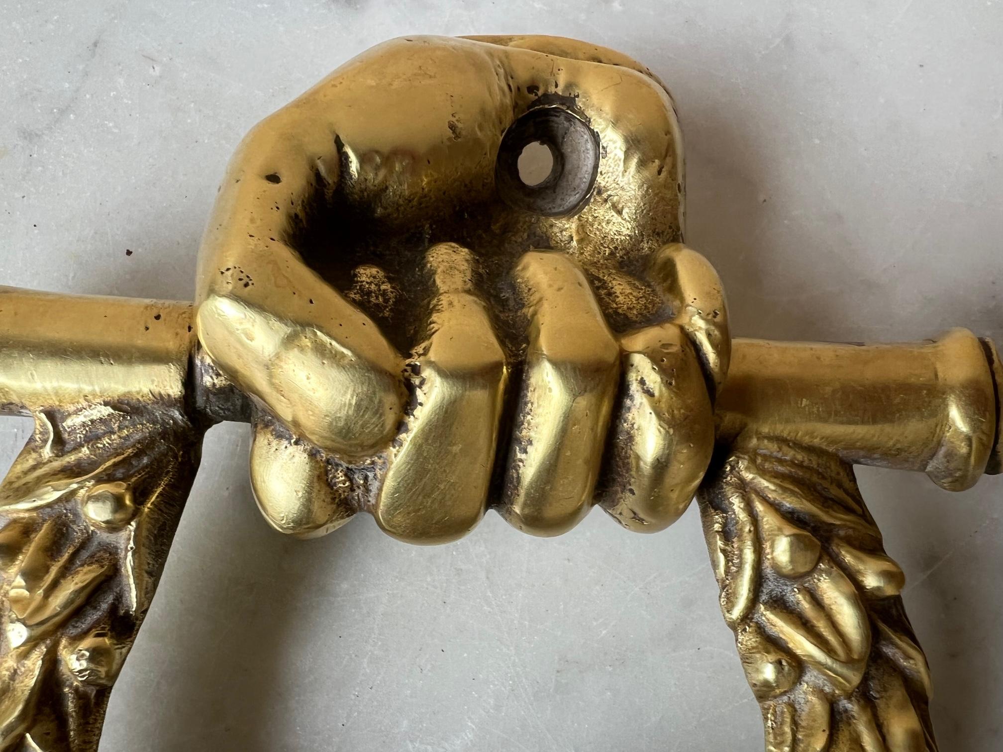 19th century brass door knocker in the form of a hand holding a laurel wreath and a lions head.
