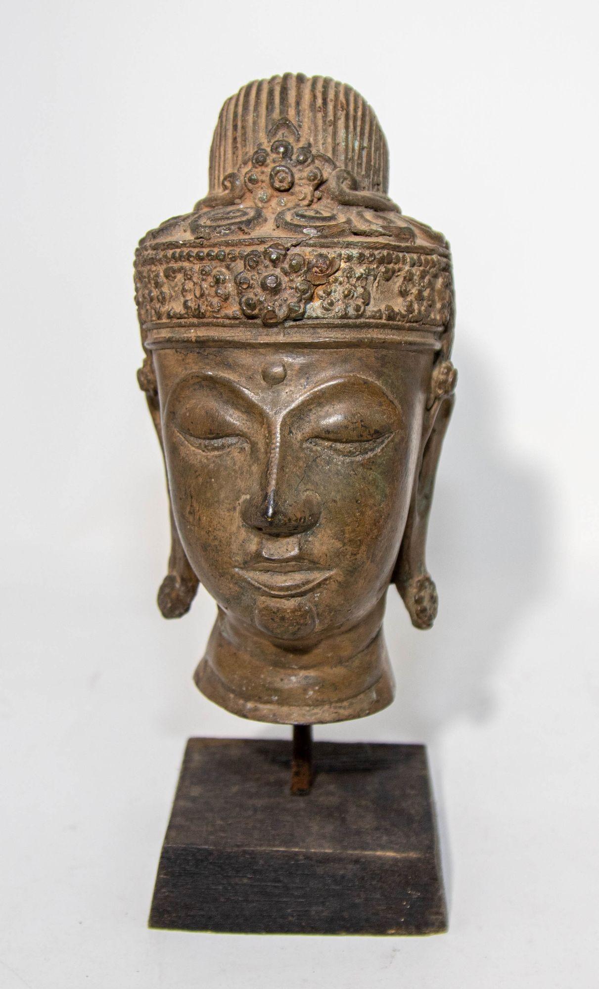Antique Southeast Asian cast bronze buddha head sculpture with verdigris patina mounted on a black base wood stand.
Bronze Sukhothai style Buddha bronze head with green patina, from North Thailand.
The head is sensitively rendered with a softly