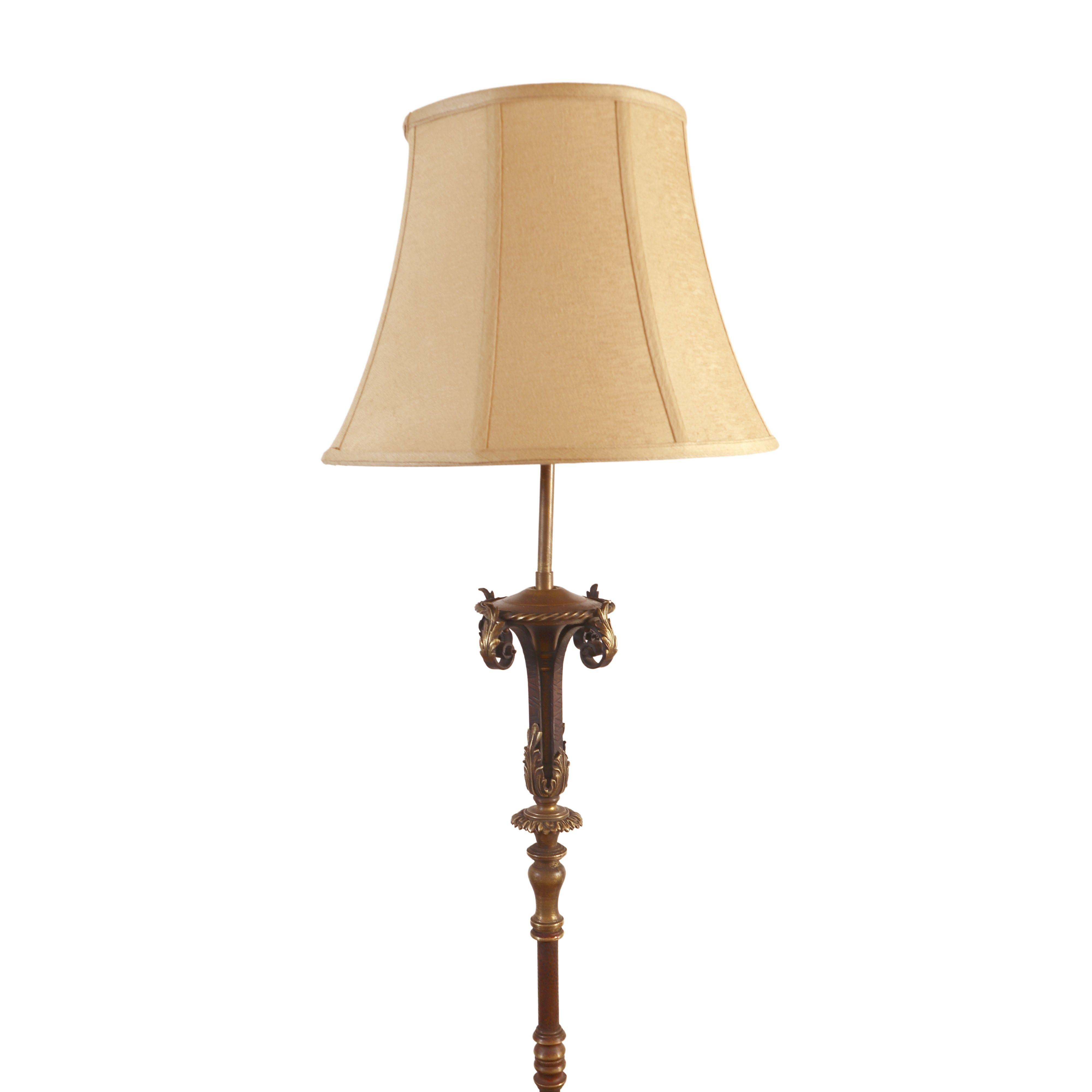 Brass and cast iron floor lamp with a black wrought iron base and beige shade. In good condition with appropriate wear from age. One available. Cleaned and restored. Please note, this item is located in one of our NYC locations.