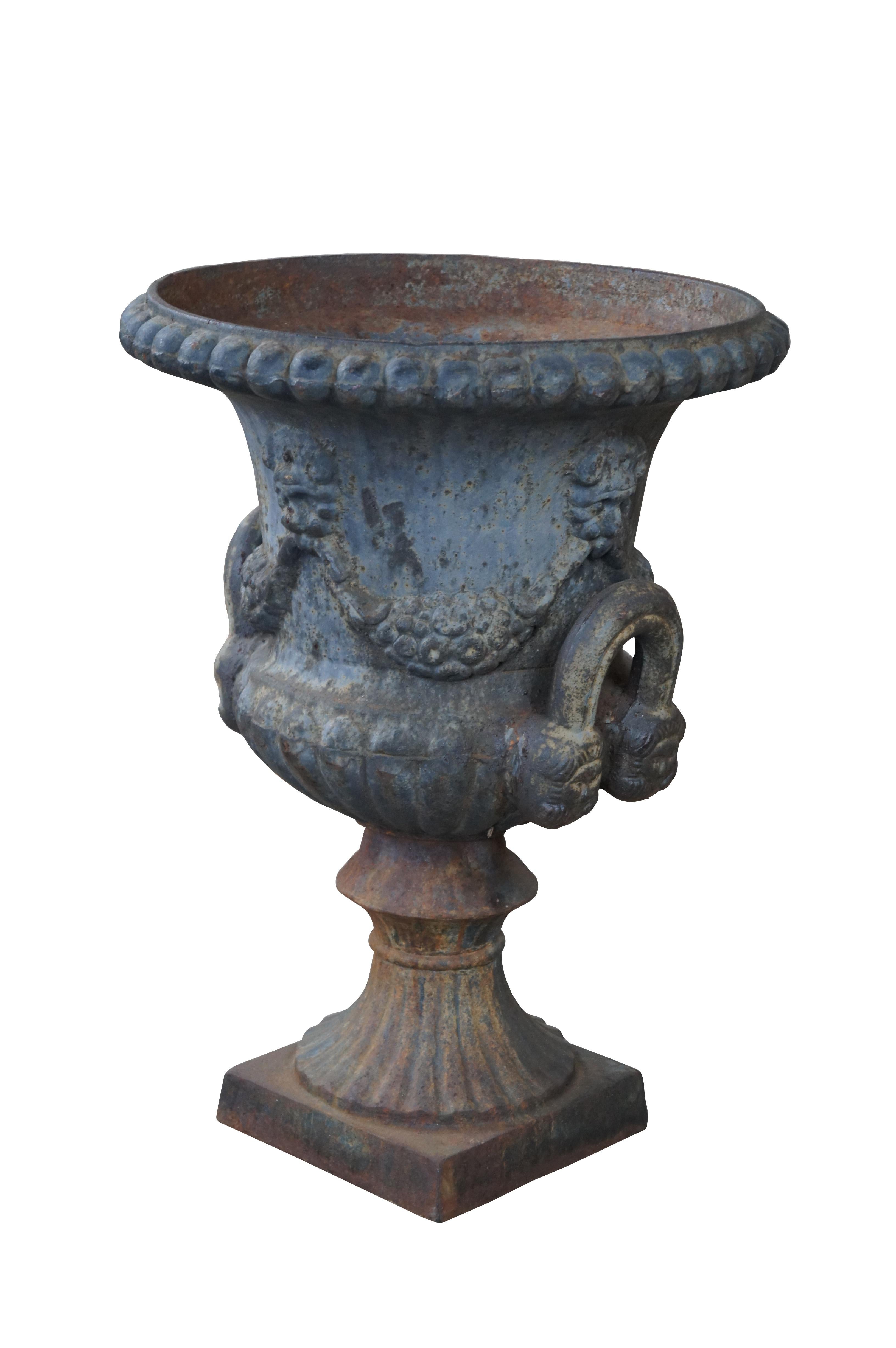 Large antique classical Grecian style urn. Made from cast iron with a flared and ribbed mouth over a grape decorated body with large handles leading to a fluted bottom over a plinth base.

Dimensions:
17